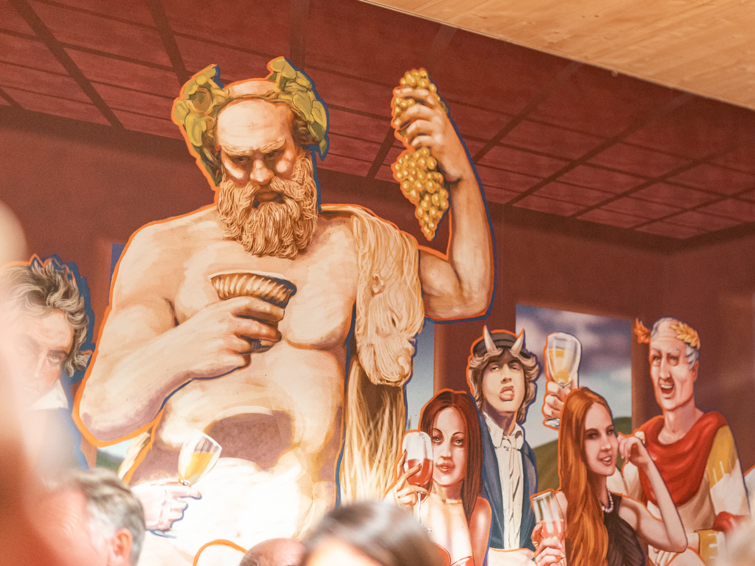 Wandgemälde des griechischen Gottes Bacchus, der Trauben hält, umgeben von Menschen.