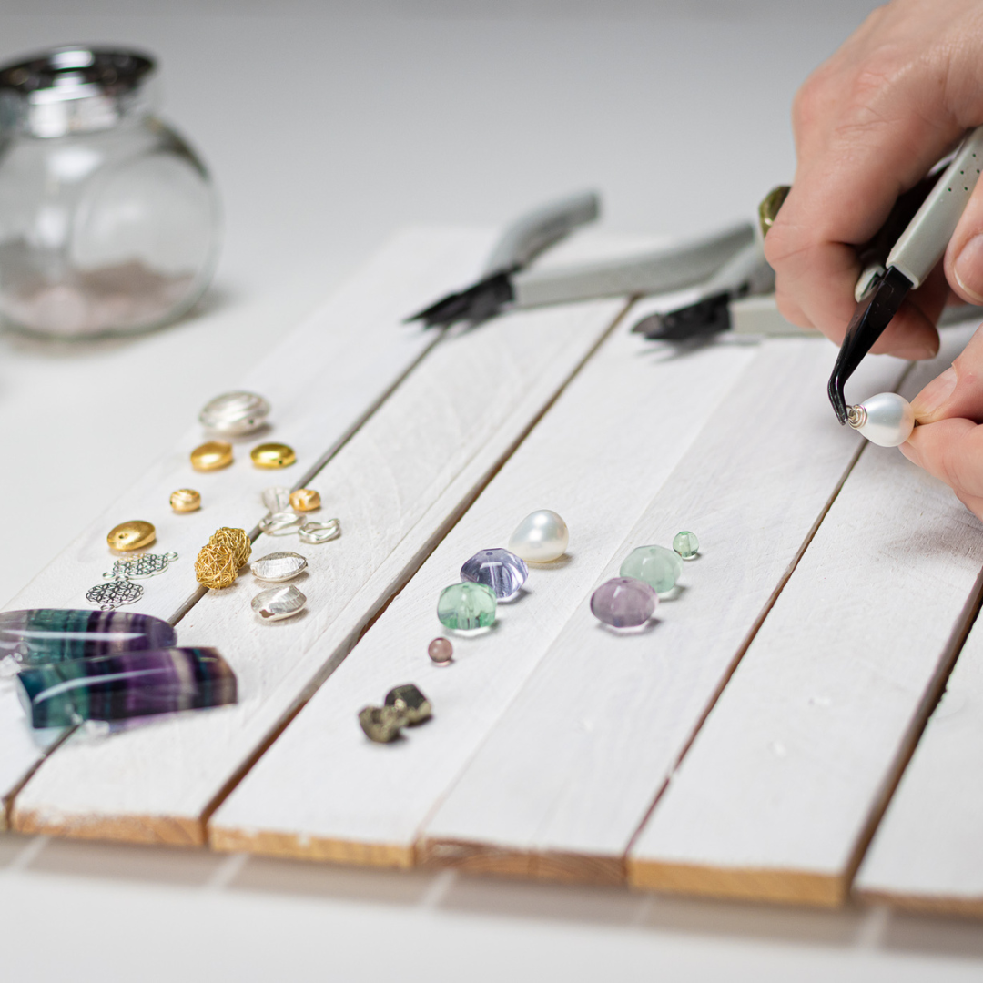 Handgefertigter Schmuck mit Perlen und Werkzeugen.