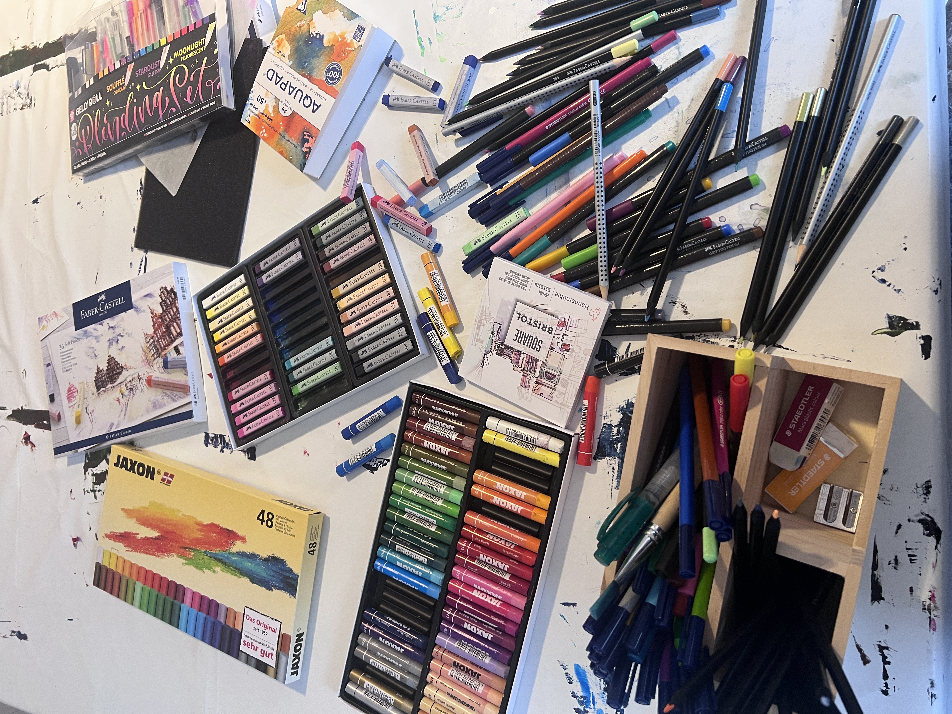 Kunstbedarf mit Wachsmalstiften, Stiften und Skizzenblock.