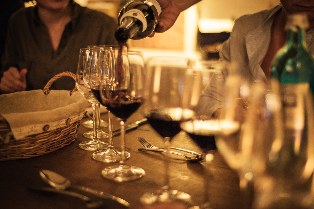 Wein wird in Gläser auf Tisch eingeschenkt.