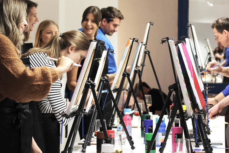People painting on canvases in a studio.