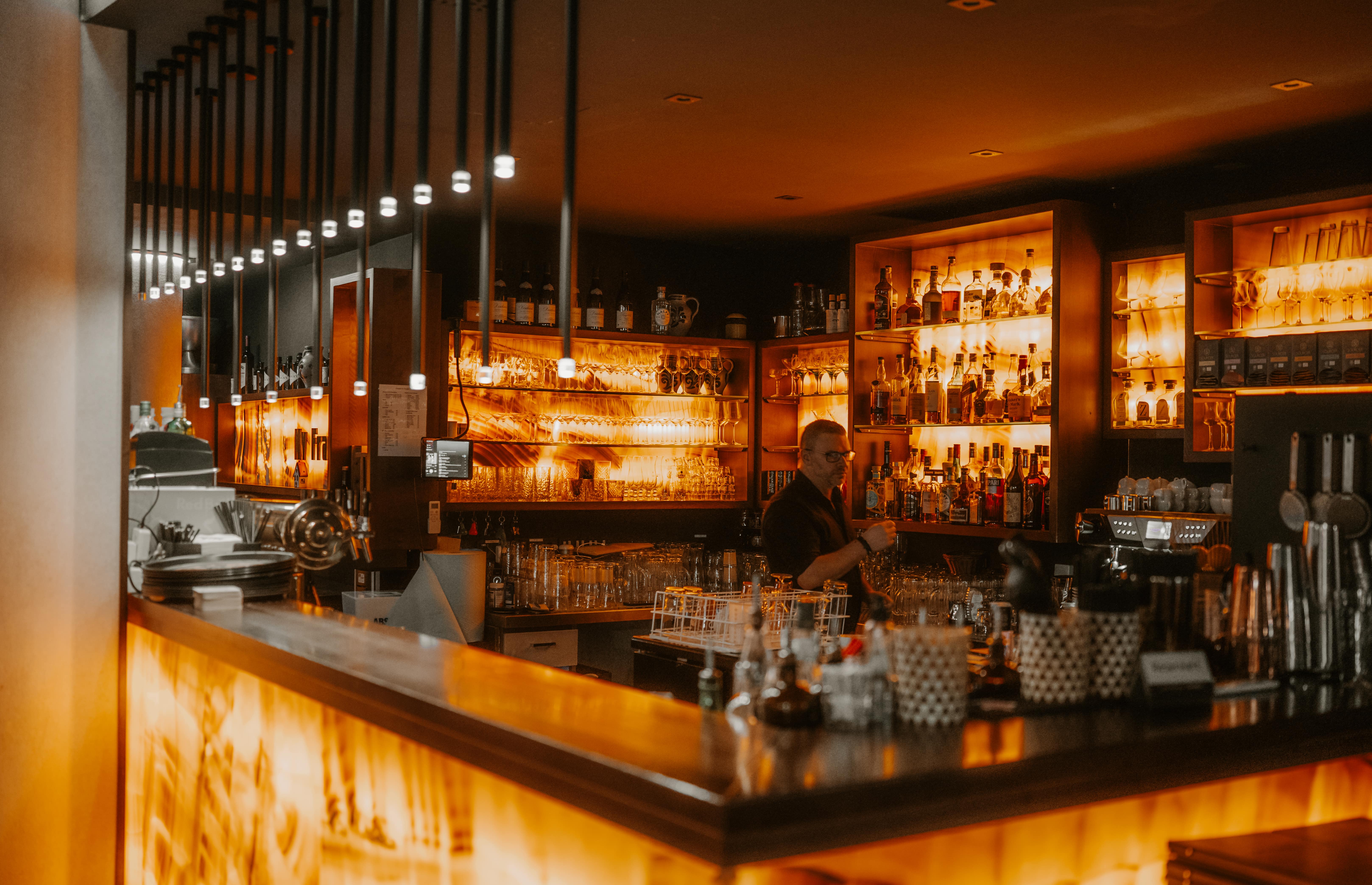 Barkeeper arbeitet hinter einer schummrig beleuchteten Bar.
