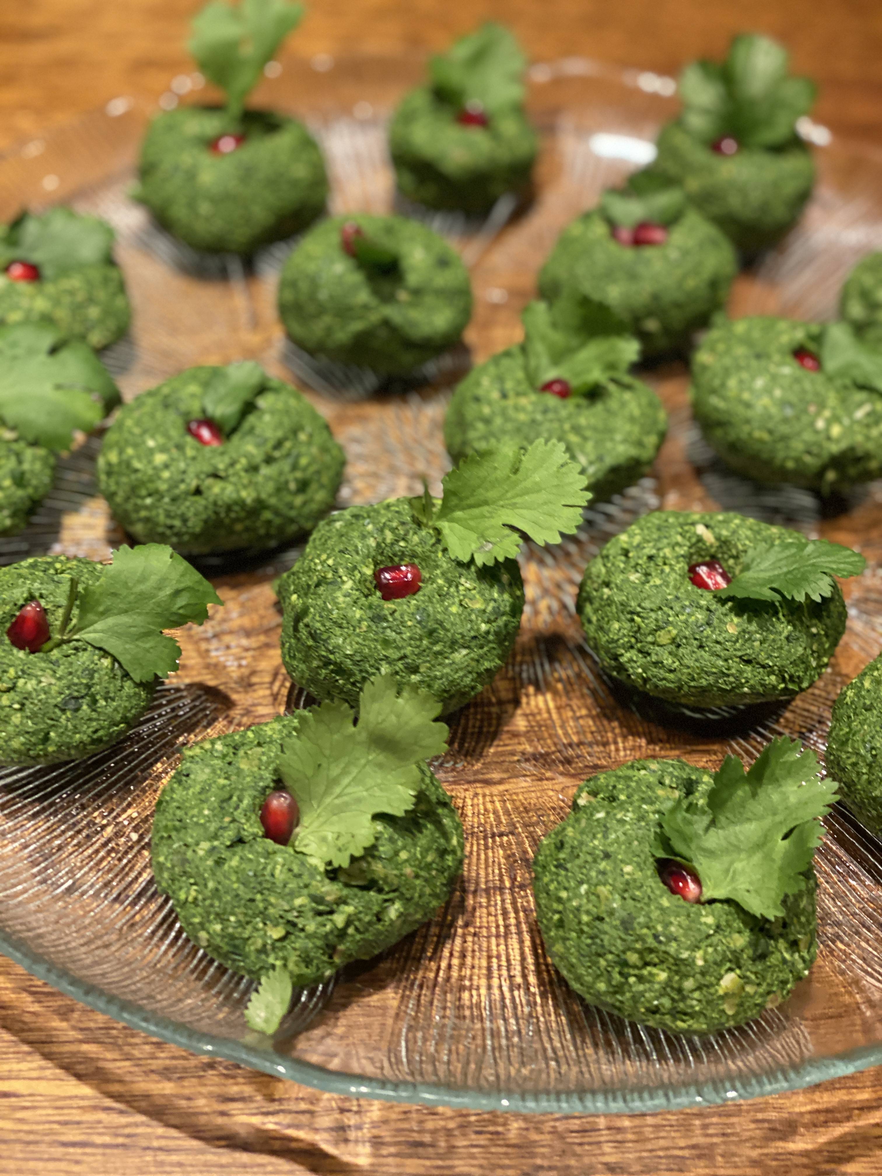 Green appetizers on glass plate, garnished with herbs.