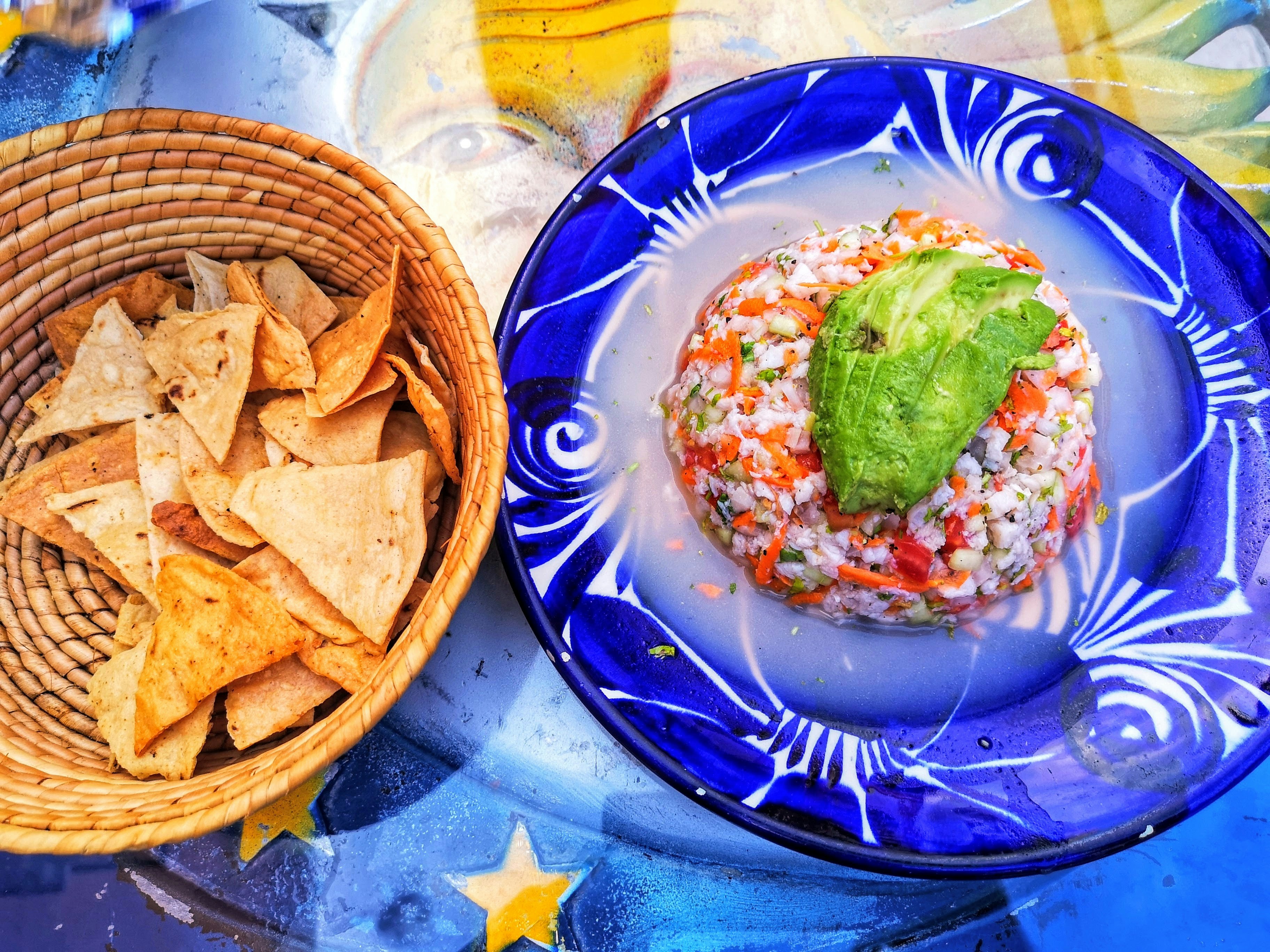 Ceviche auf Teller mit Chips im Korb.
