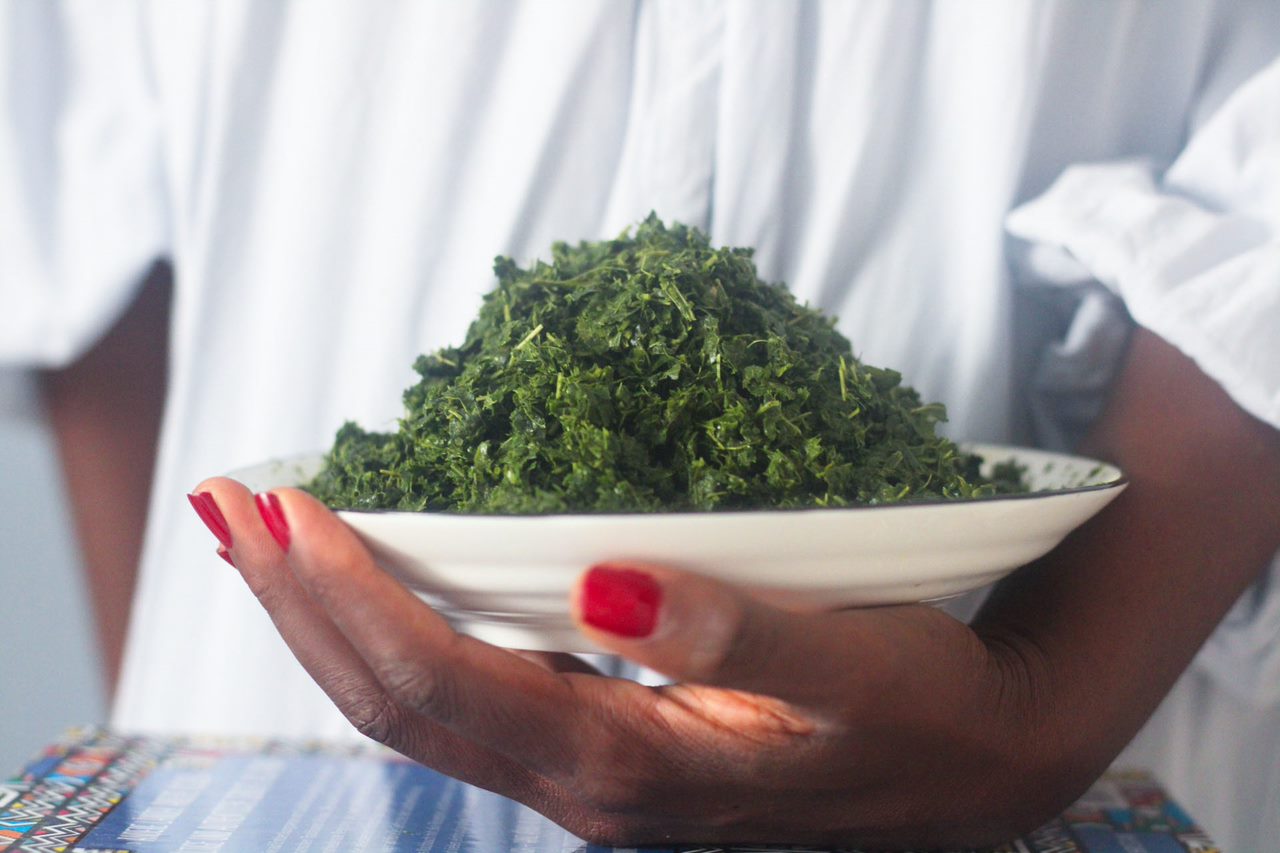 Person holding a plate of leafy greens.
