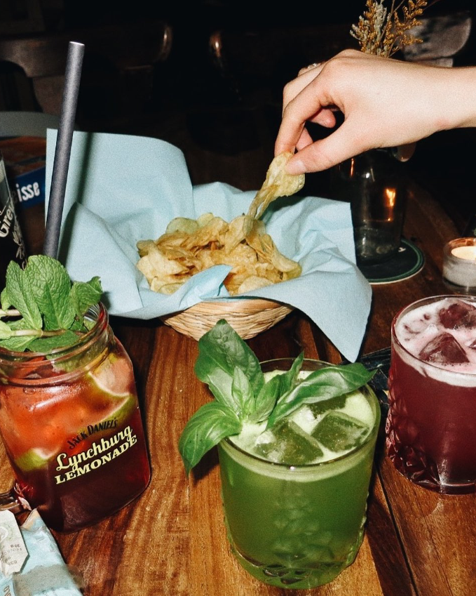 Drei bunte Cocktails auf einem Holztisch.