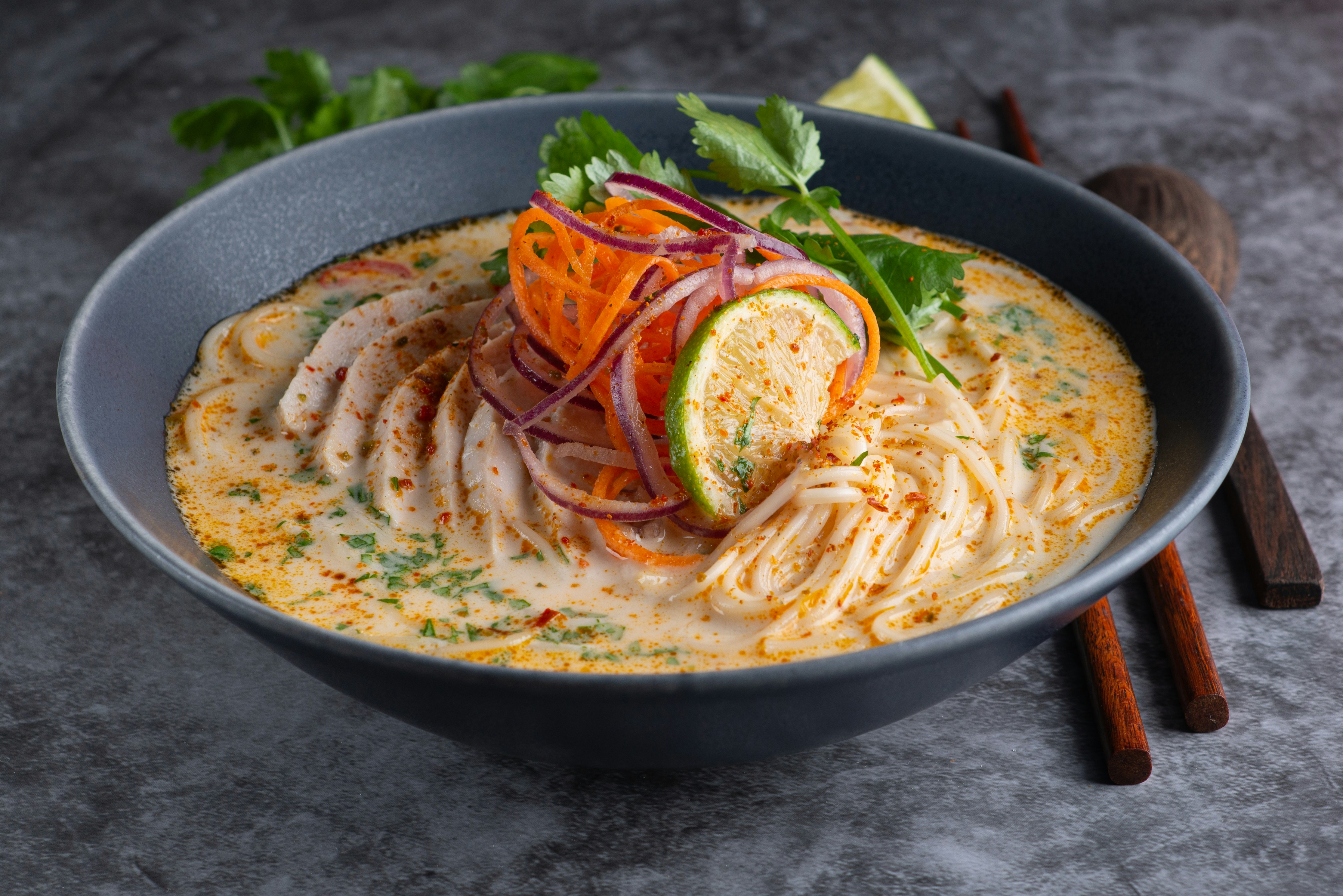 Bowl of noodle soup garnished with vegetables.