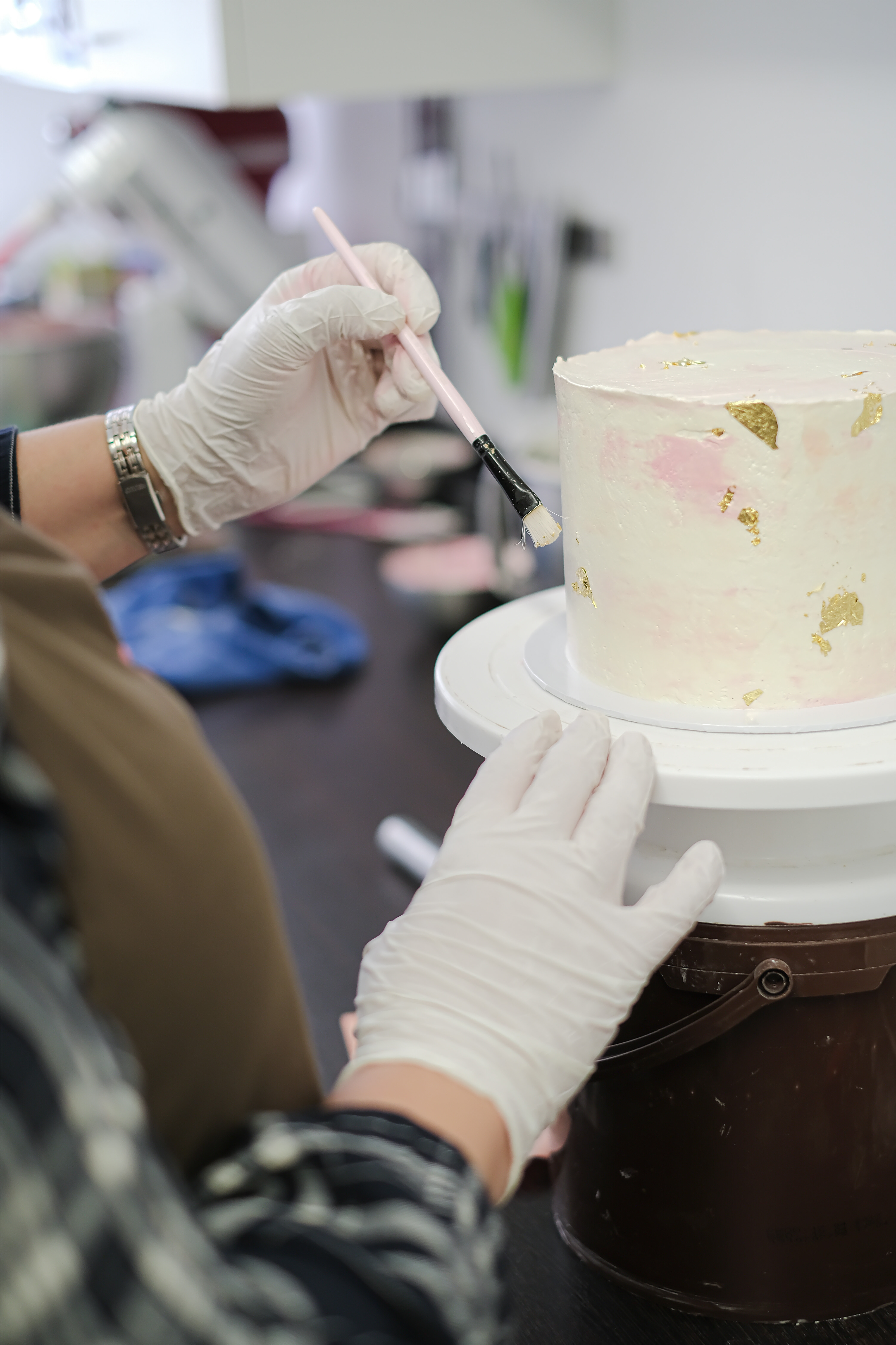 Behandschuhte Hand bemalt weißen Kuchen mit Pinsel.