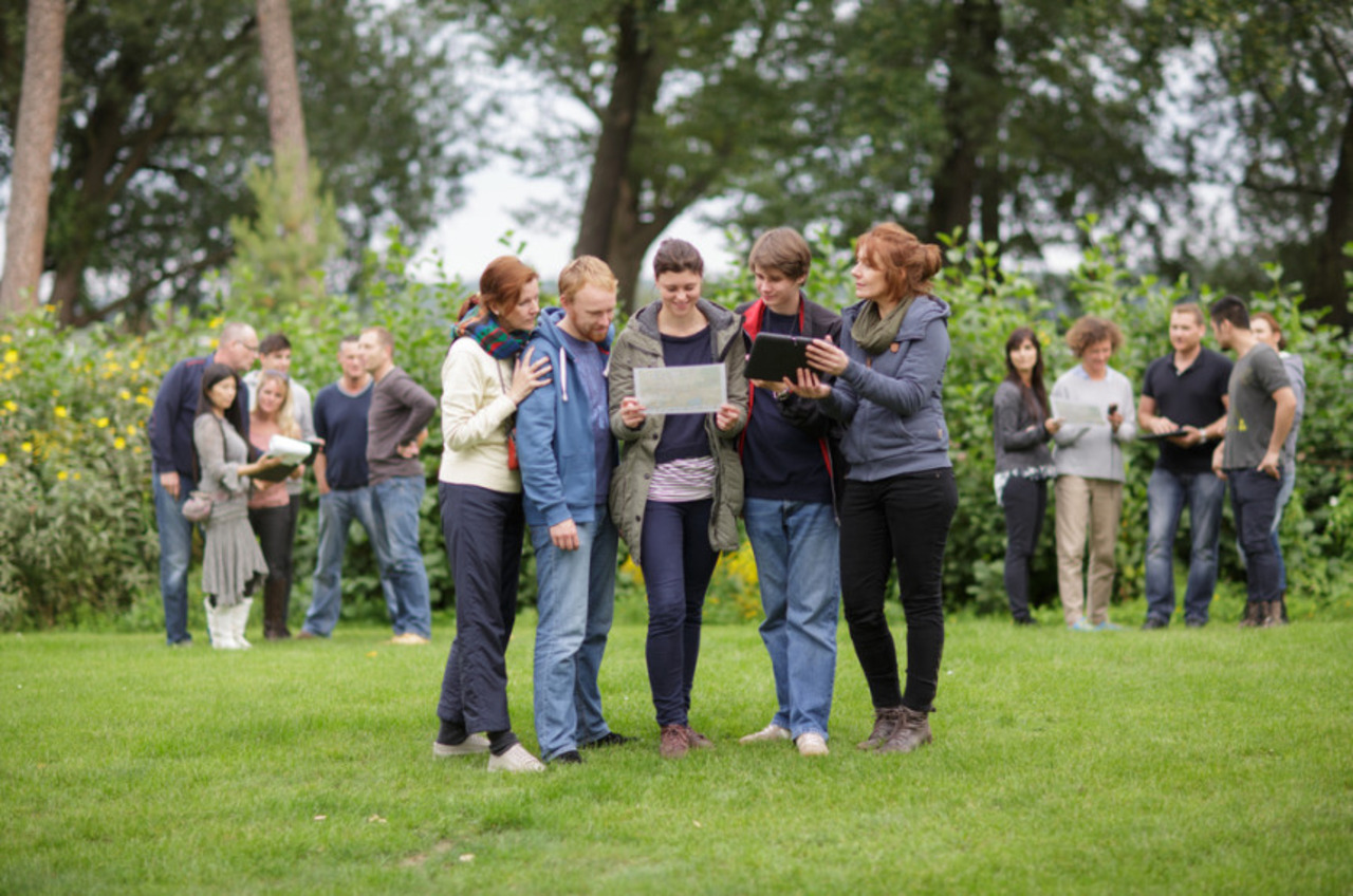 Gruppe von Leuten untersucht Papiere im Park.