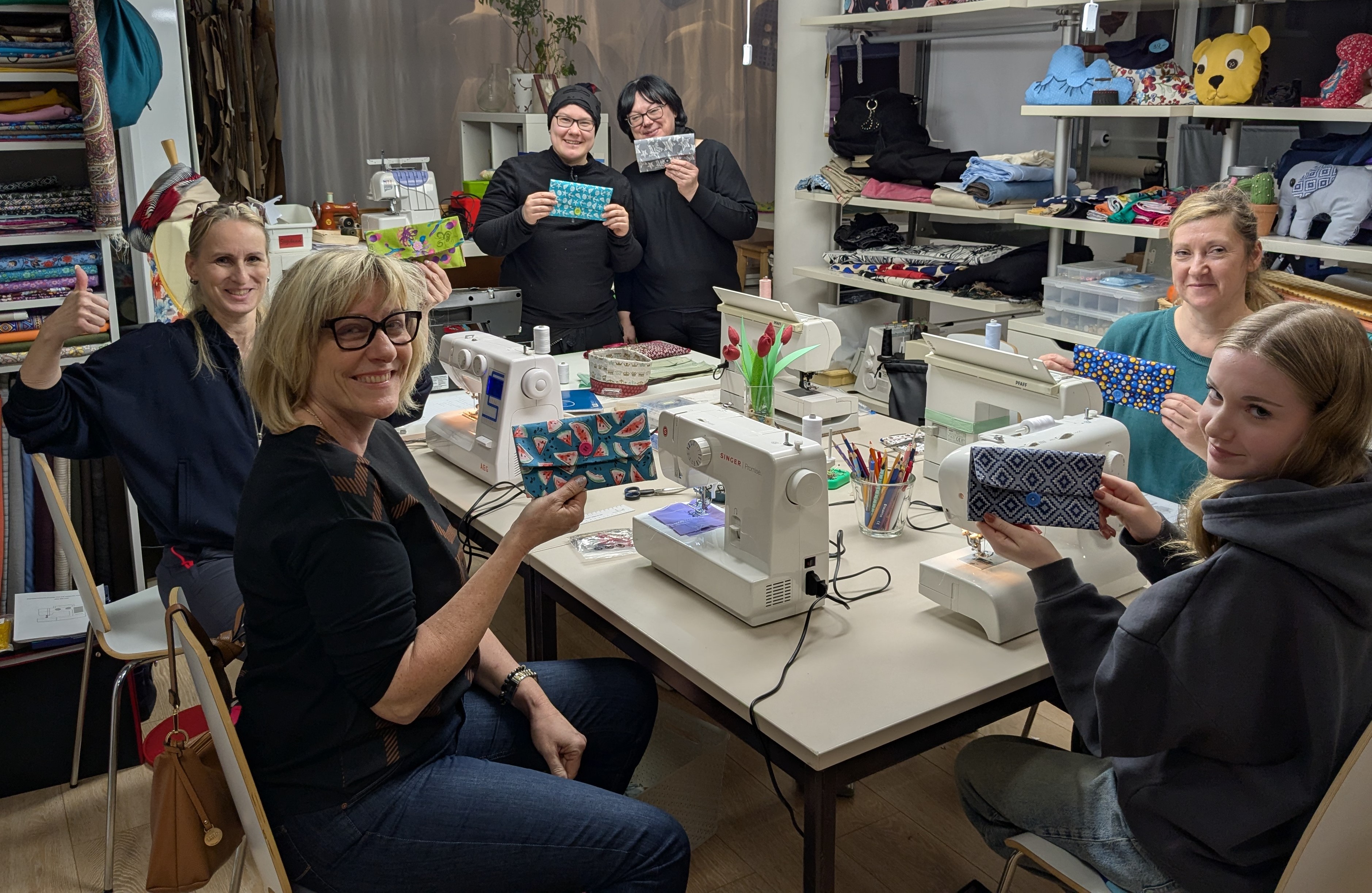Group sewing at table with machines.