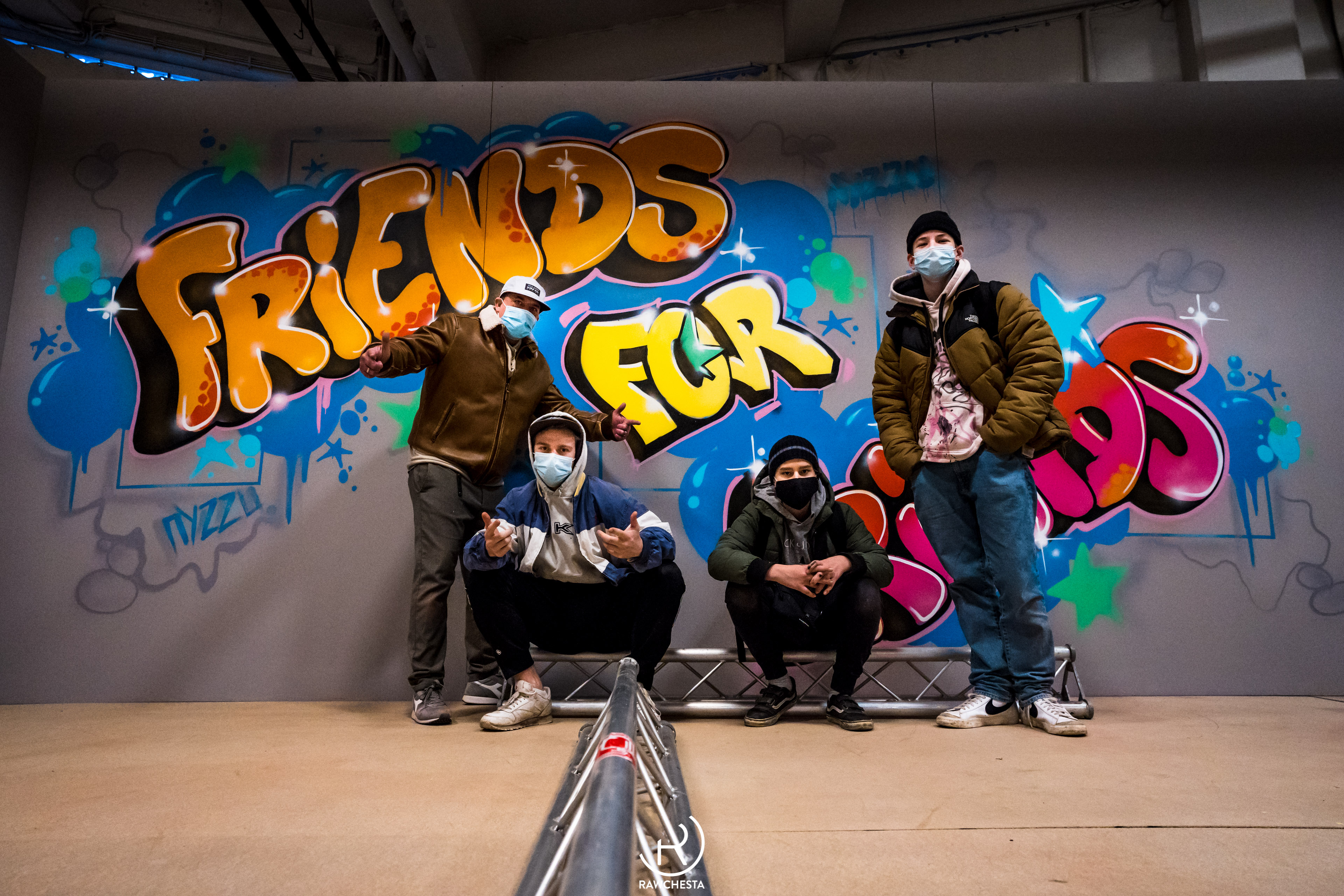 Vier Personen posieren vor Graffiti-Wand.