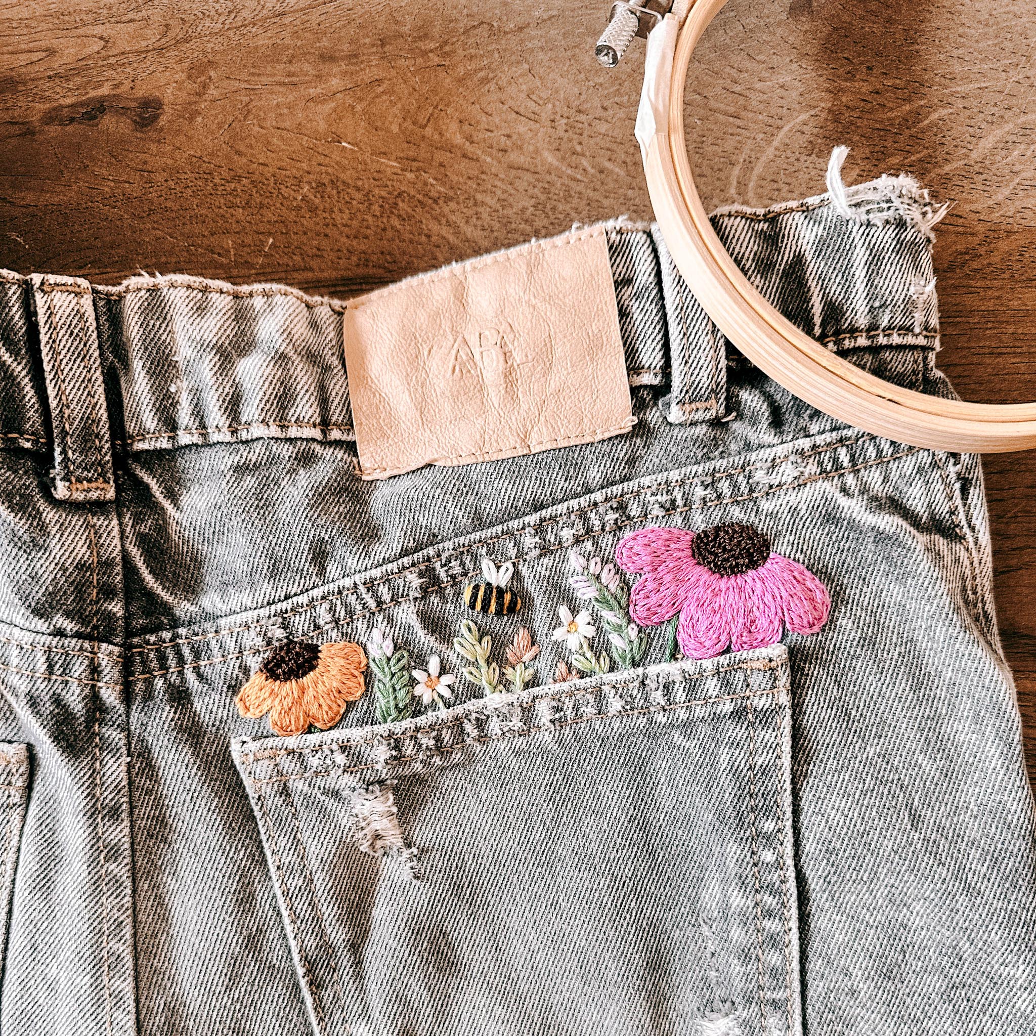 Floral embroidery on denim jeans pocket.