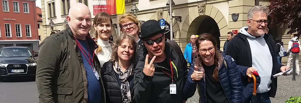 Gruppe von Menschen lächelt vor historischem Gebäude.