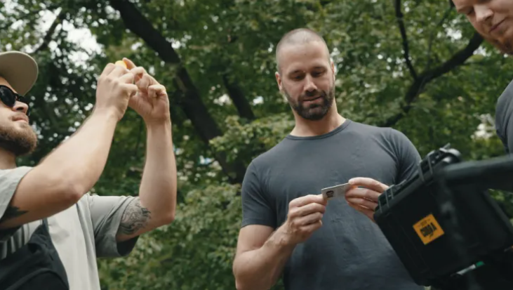 Three men examining a device in a forest.