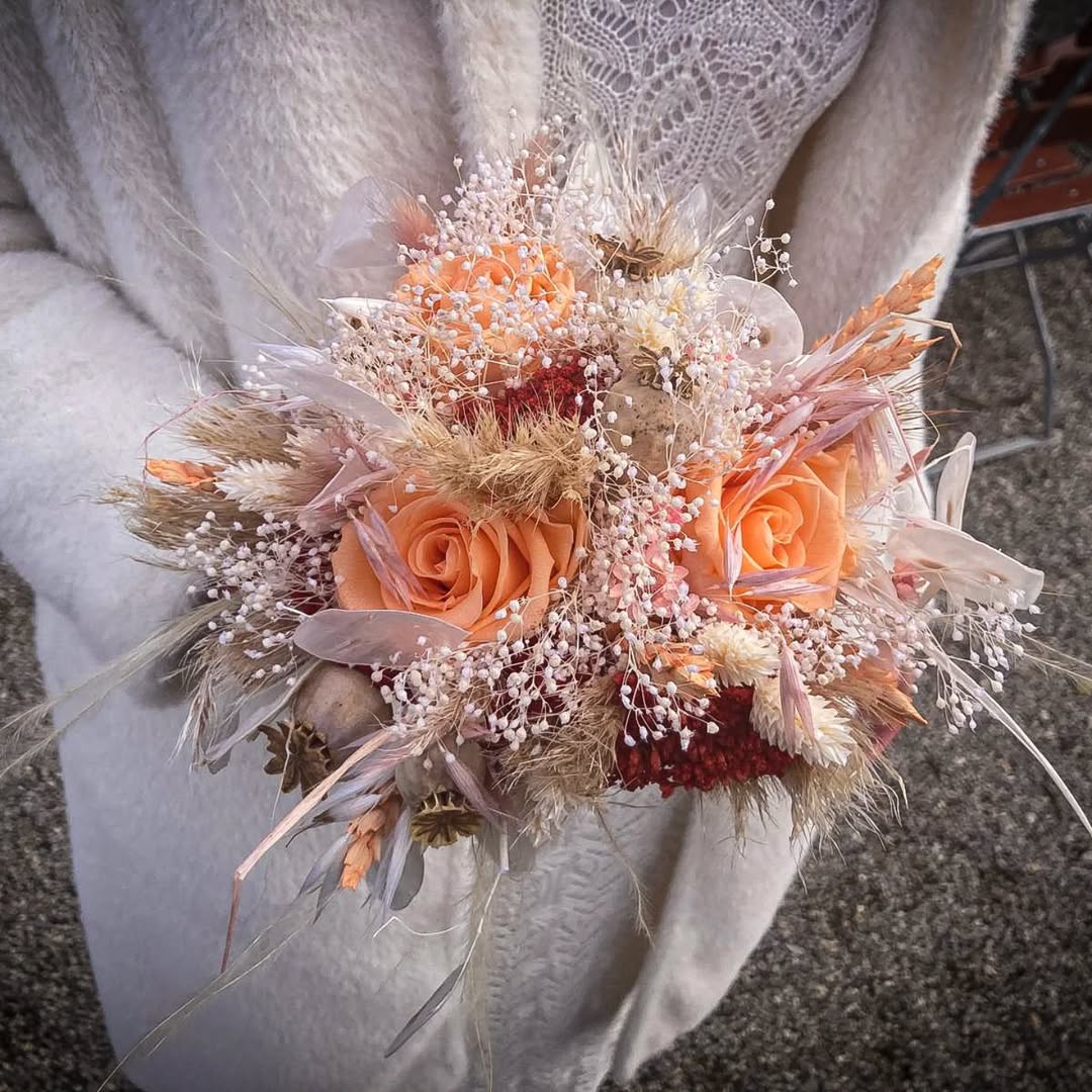 Blumenstrauß mit Rosen und Trockenblumen, draußen gehalten.