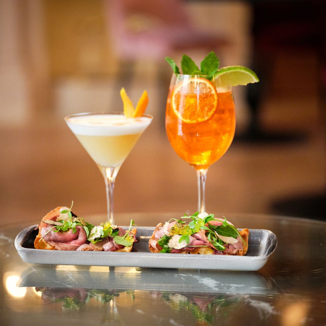 Two cocktails and appetizers on a table.