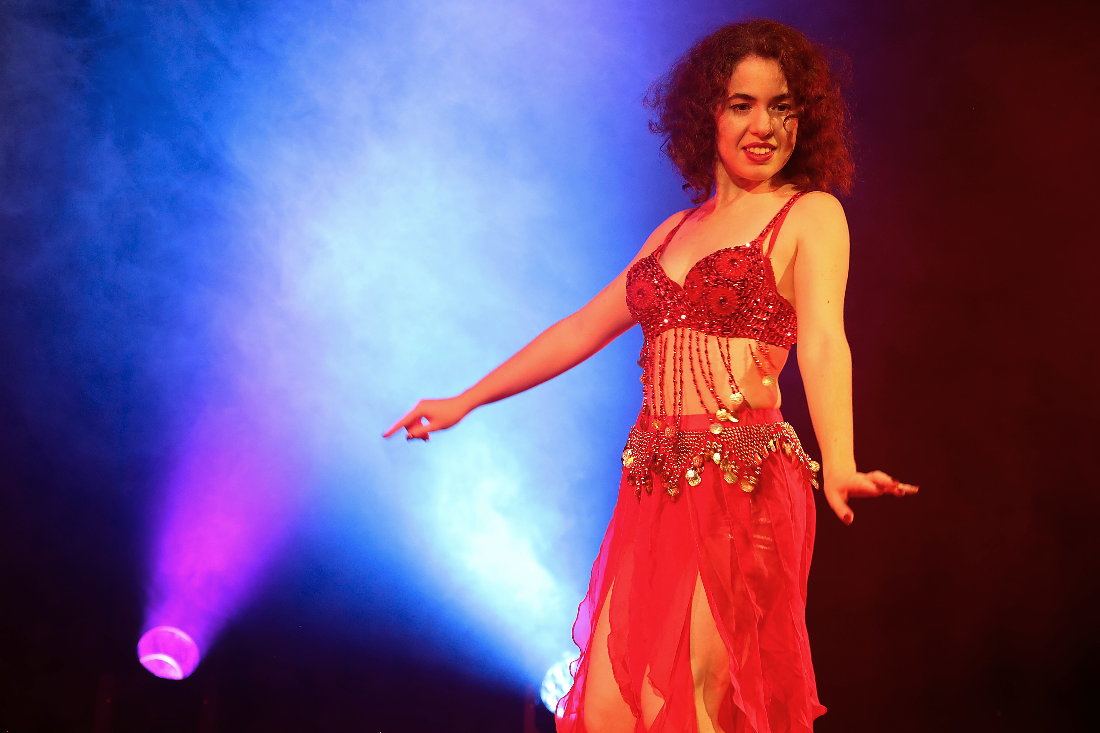 Woman belly dancing on stage with colorful lights.