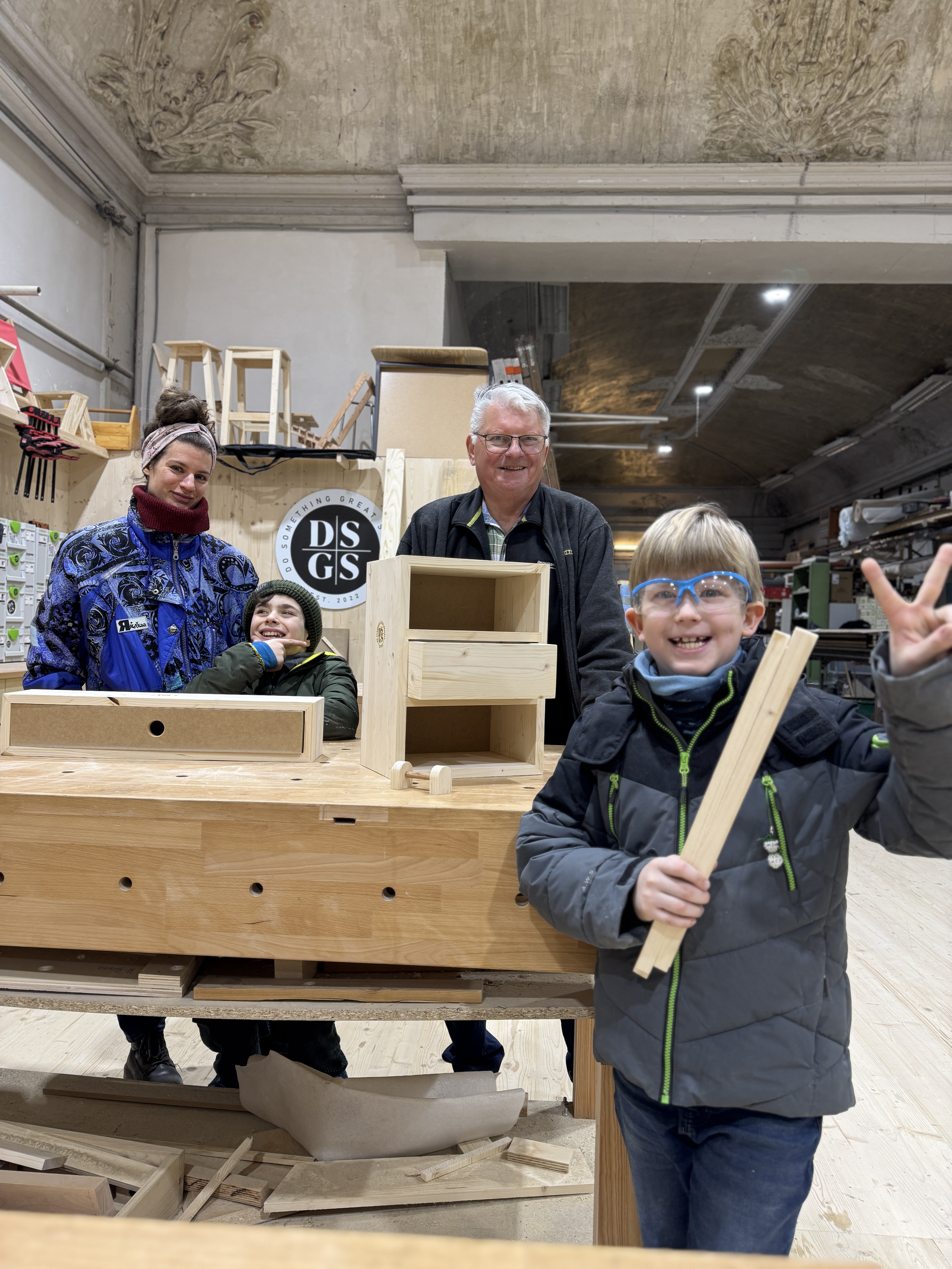 Vier Personen lächeln an einem Holztisch.