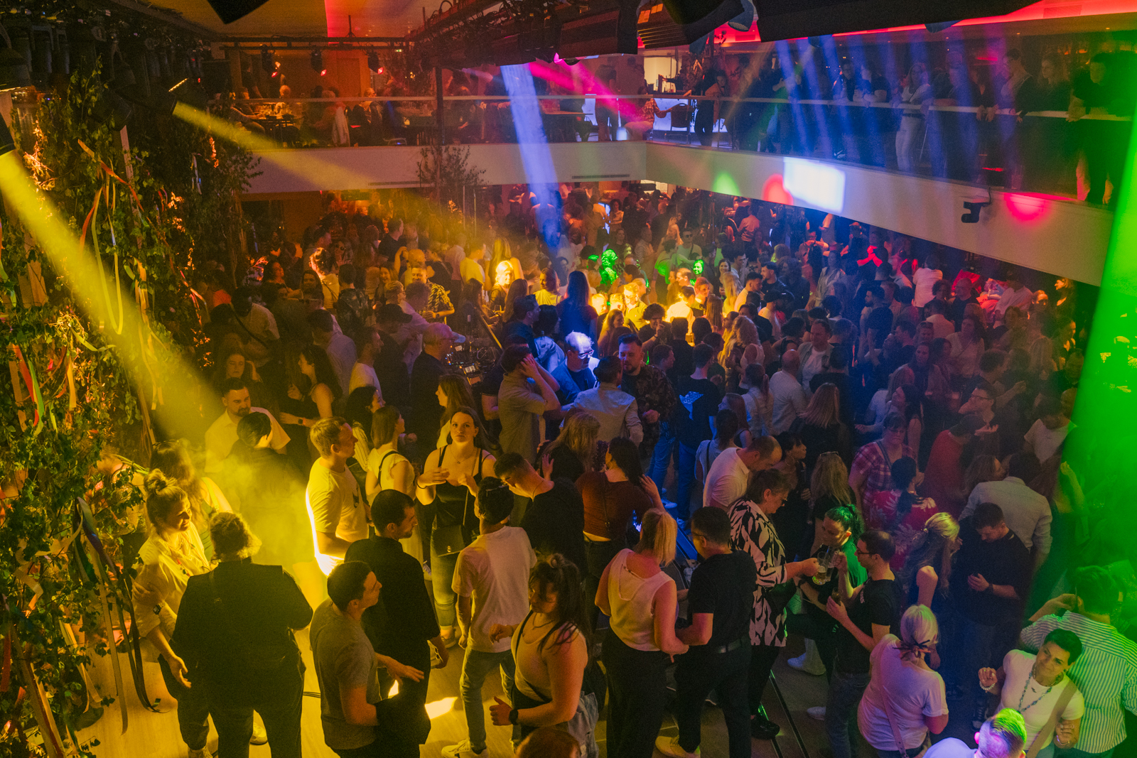 Crowded nightclub with colorful lighting effects.