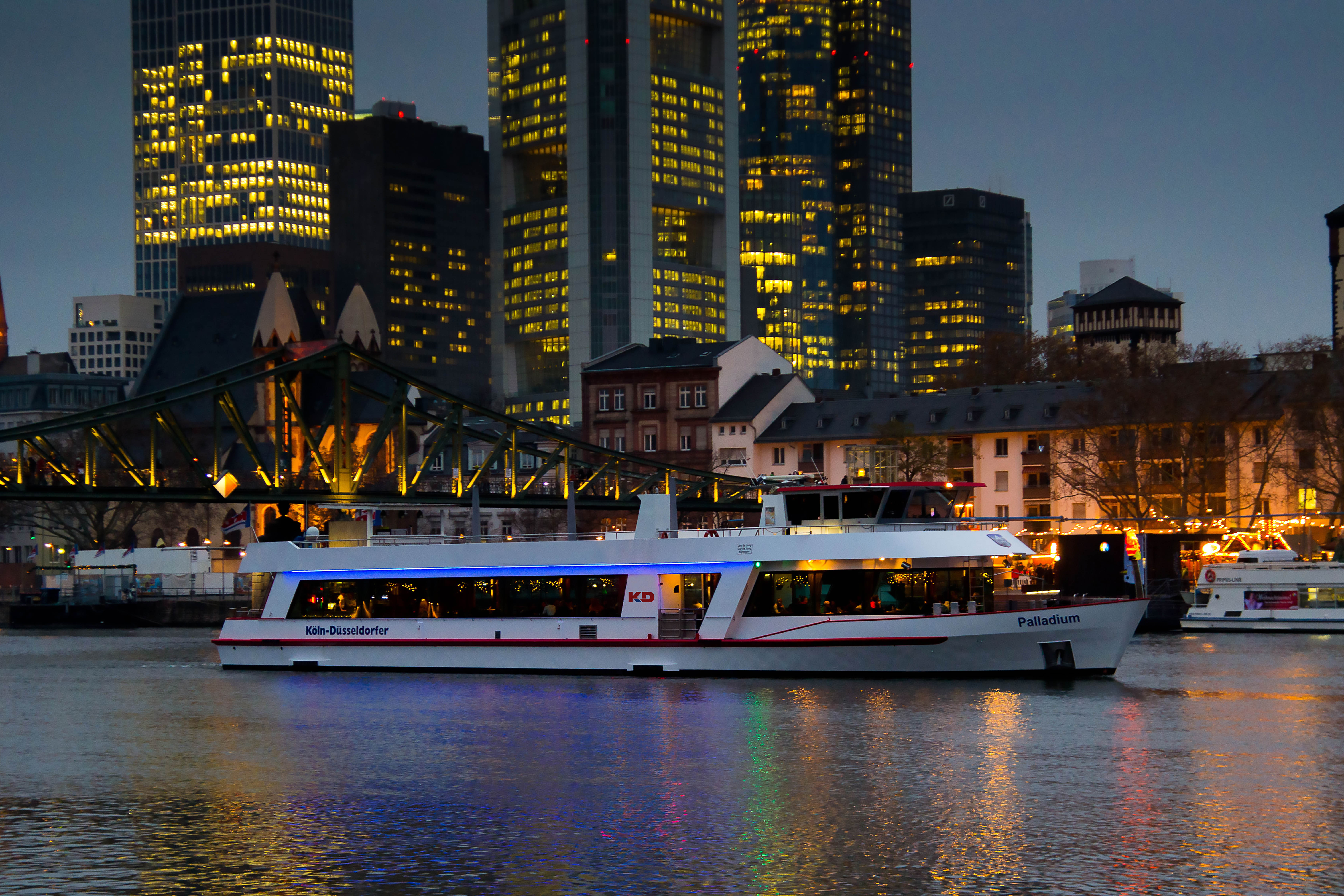 Boat sailing on river with city skyline.