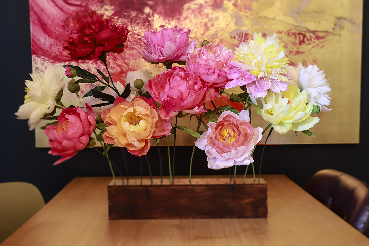 Bunte Papierblumen in einer Holzkiste.