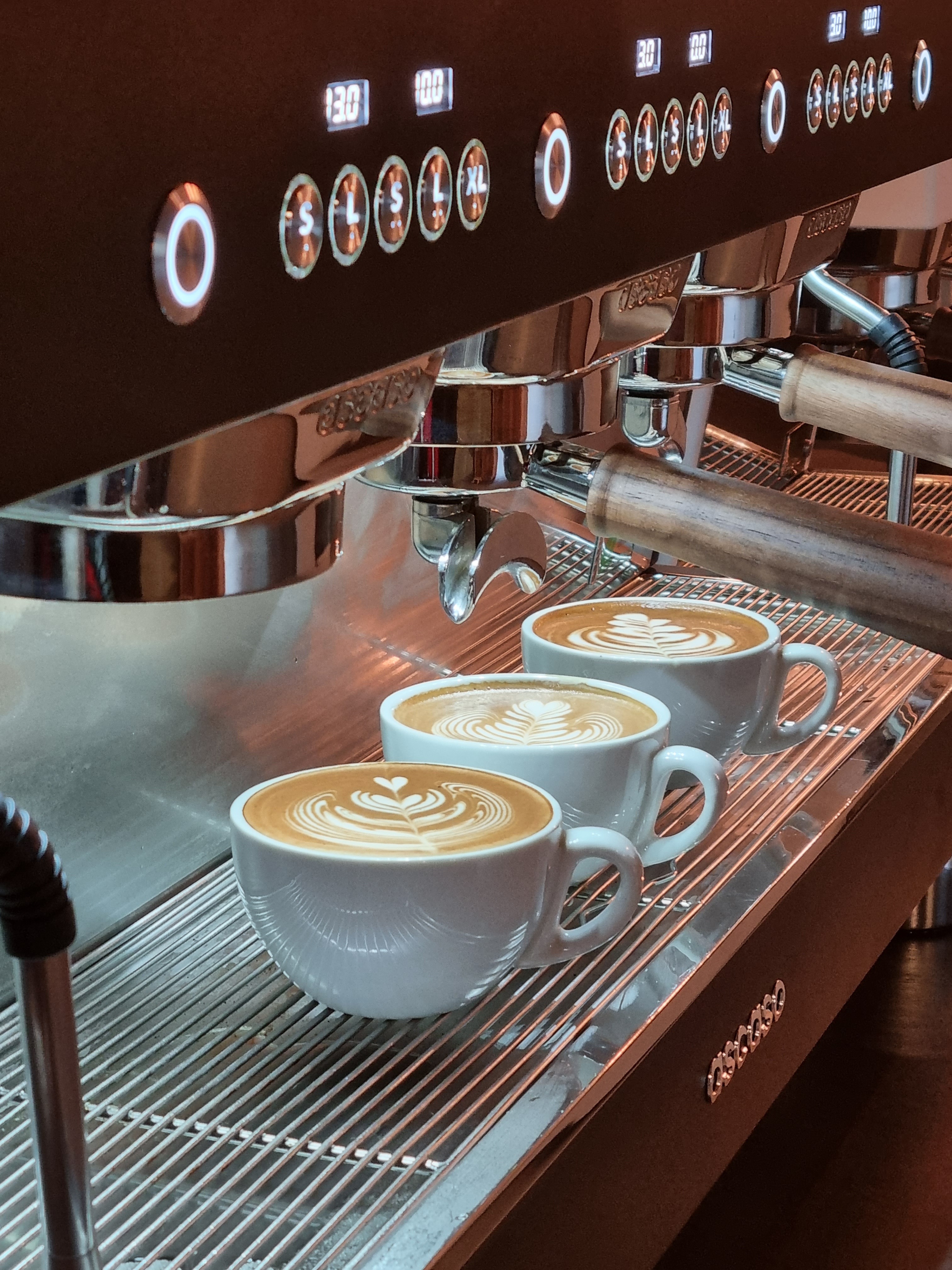 Drei Cappuccinos mit Latte Art auf Tresen.