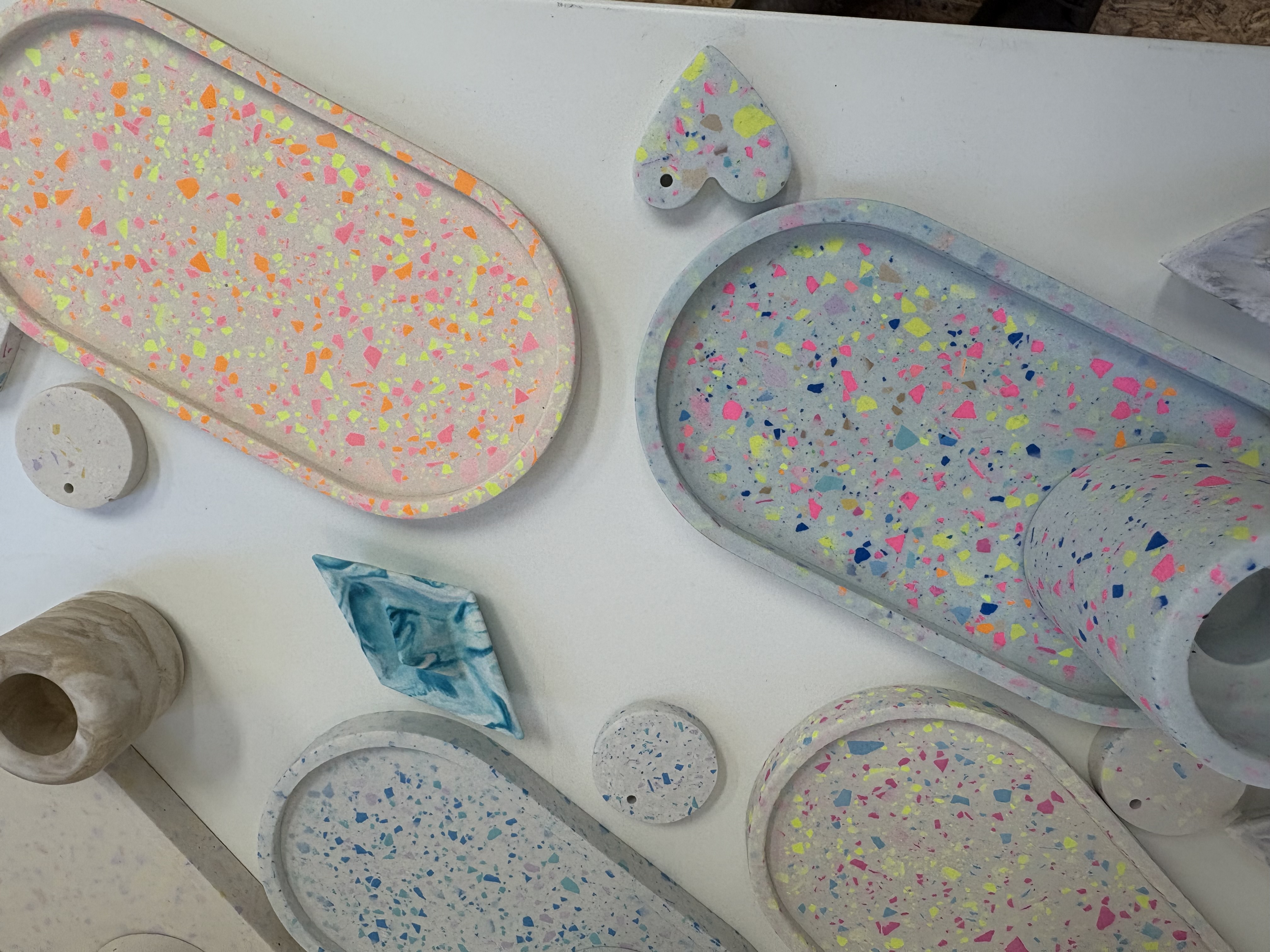 Colorful terrazzo trays and coasters on white surface.