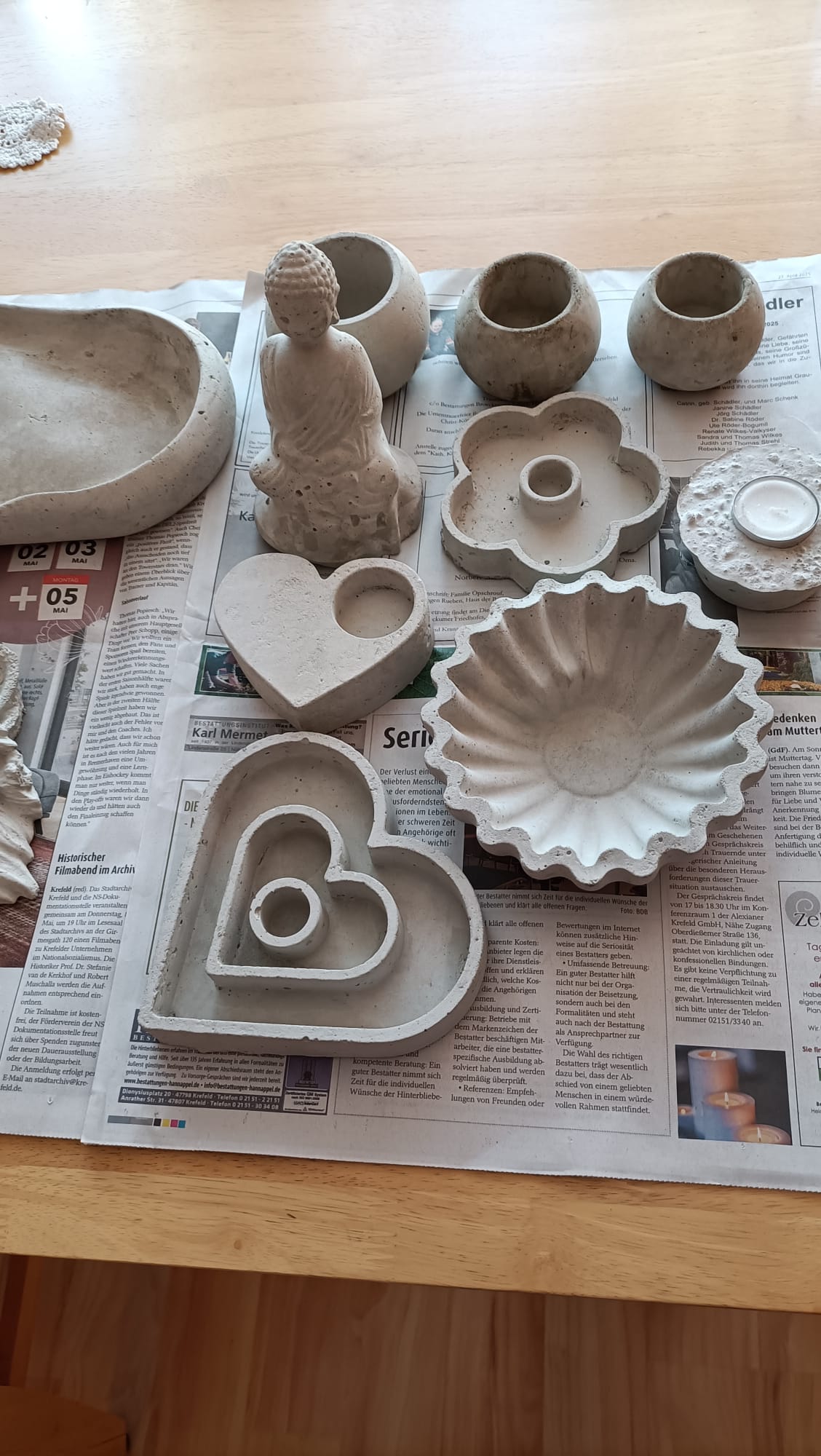 Concrete molds and objects on newspaper table.