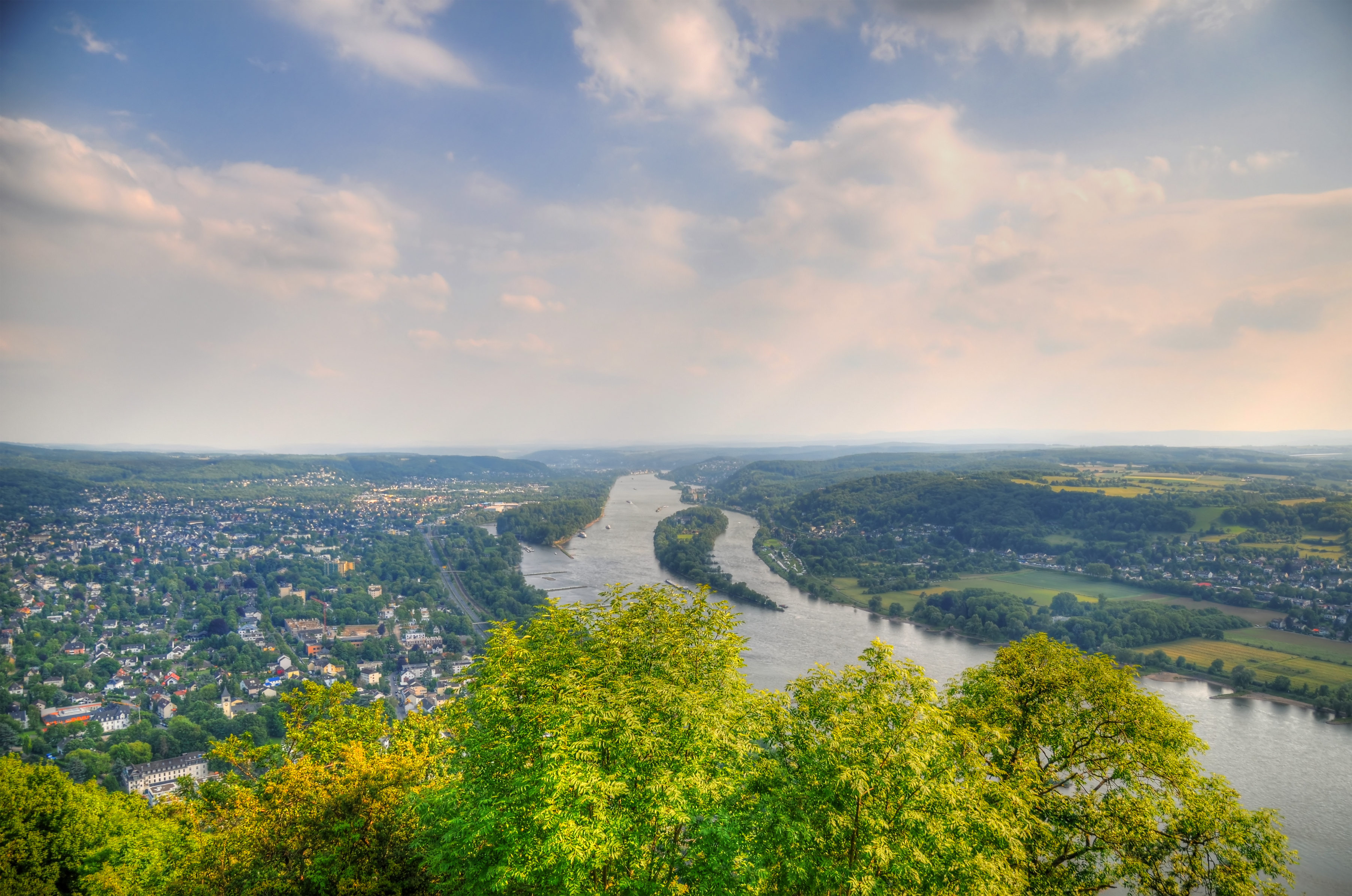 Fluss schlängelt sich durch üppiges Tal, bewölkter Himmel.