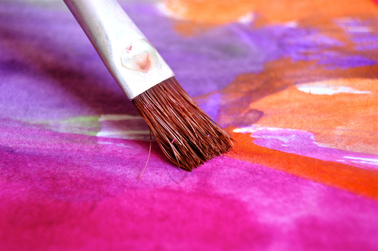 Pinsel trägt Farbe auf einer bunten Leinwand auf.