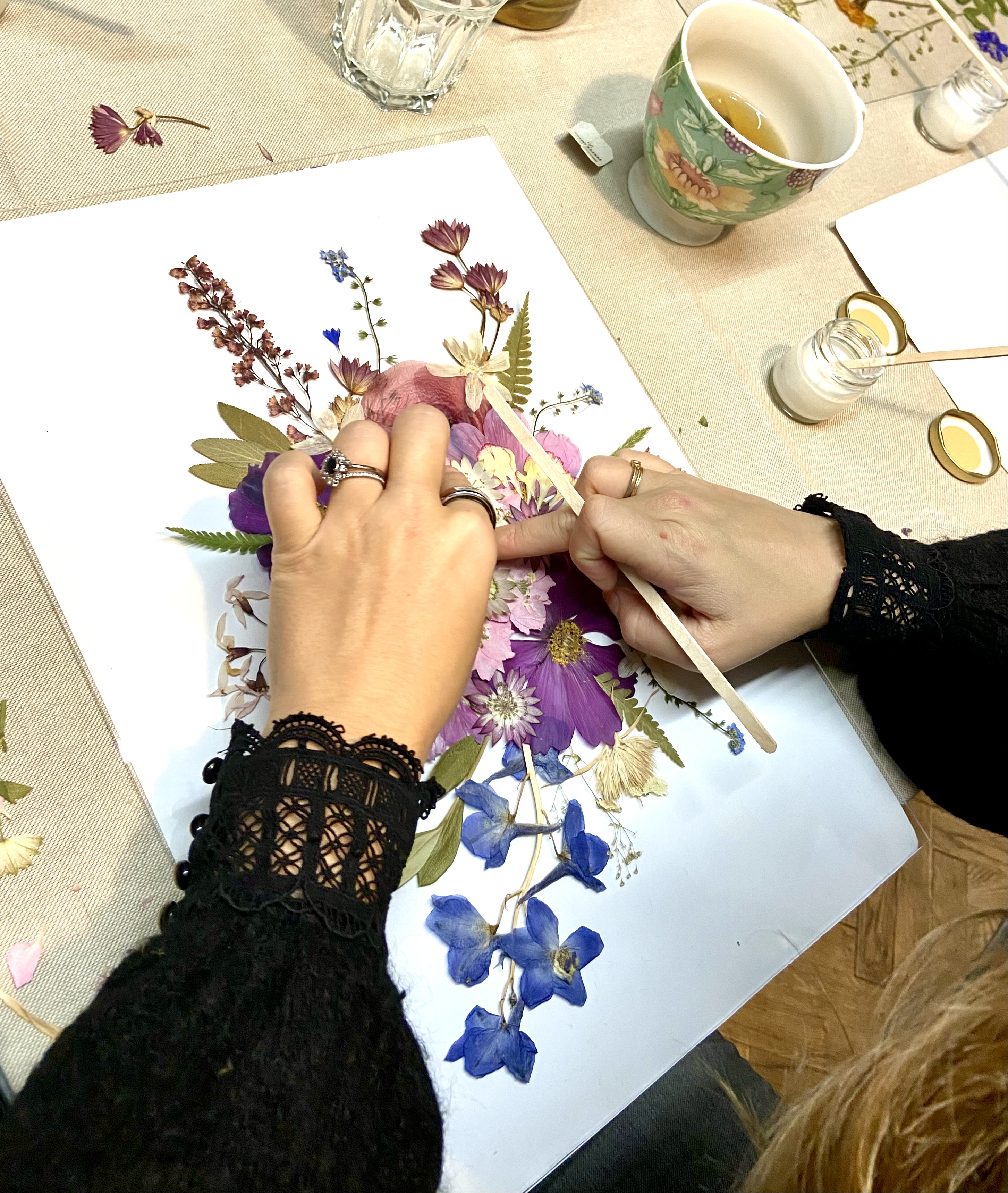 Hände arrangieren getrocknete Blumen auf Papier.