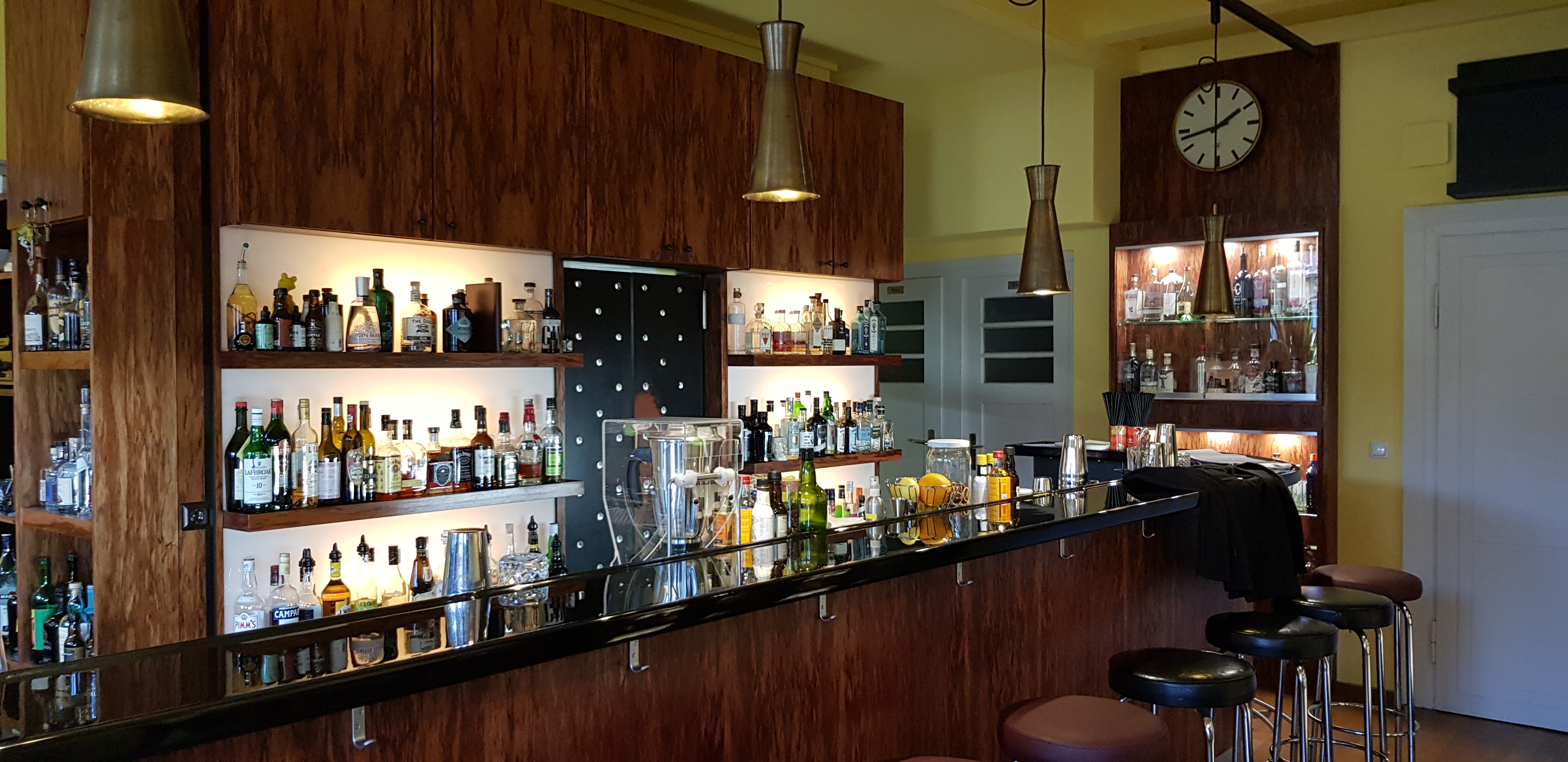 Bar mit Flaschen und Hockern, Holzinrichtung.