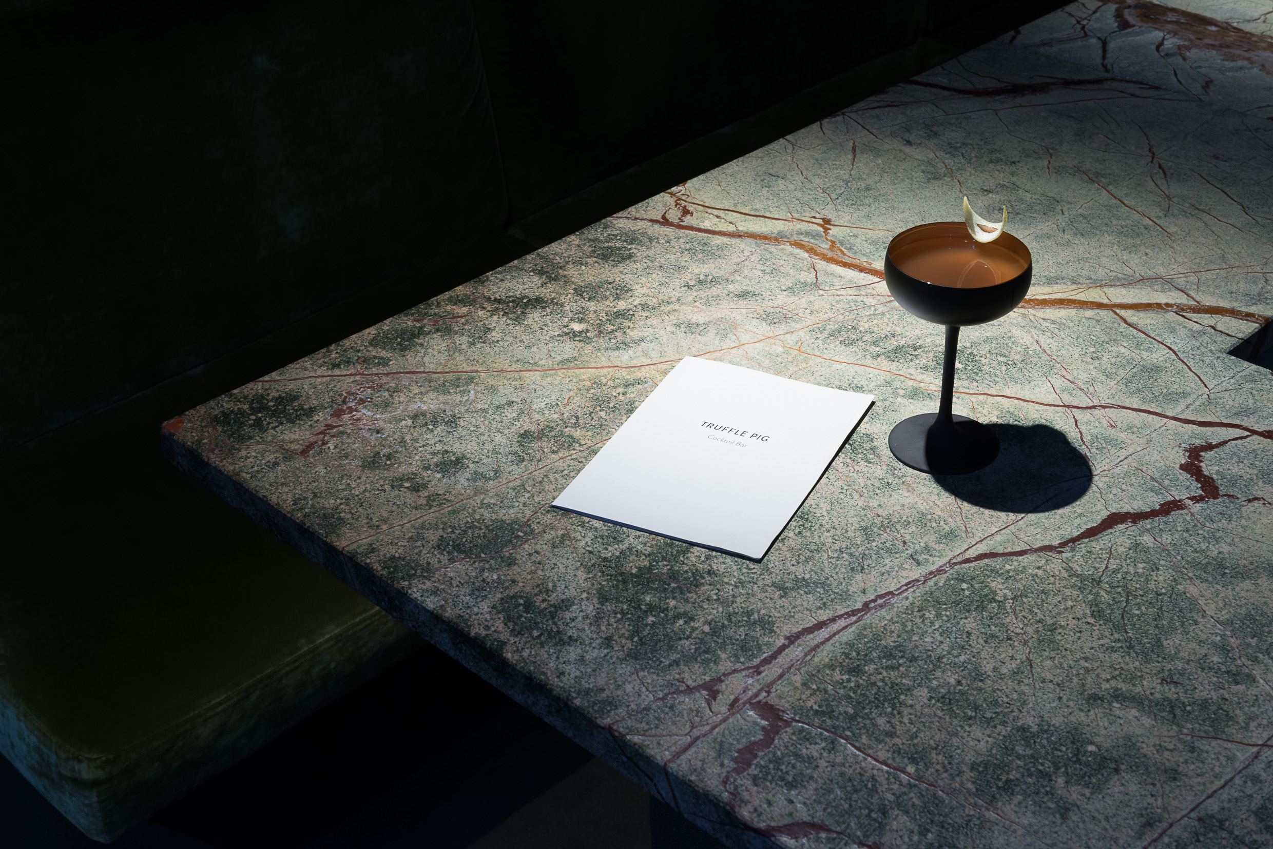 Cocktail and menu on marble table.