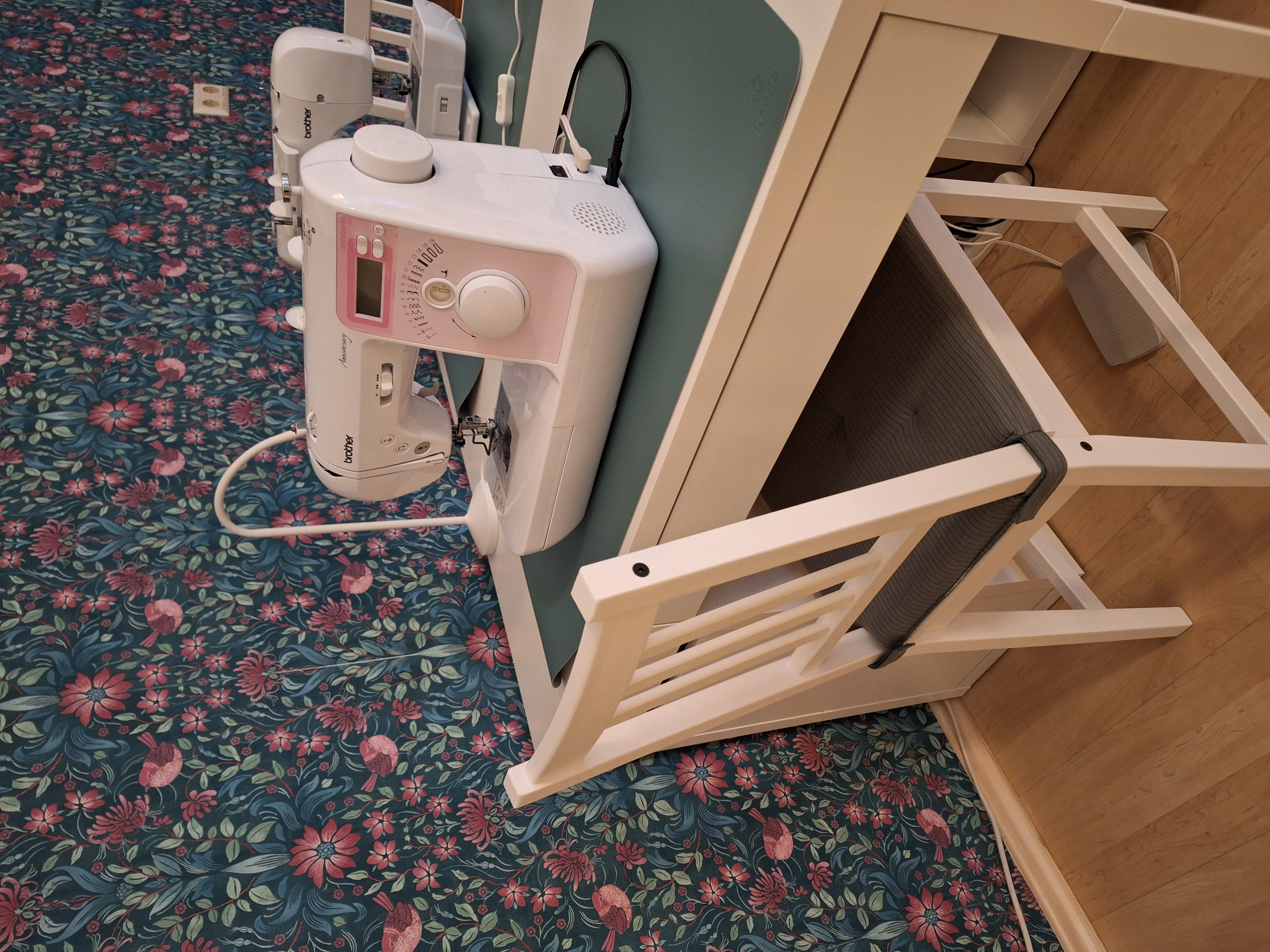 Sewing machine on table, floral wallpaper background.
