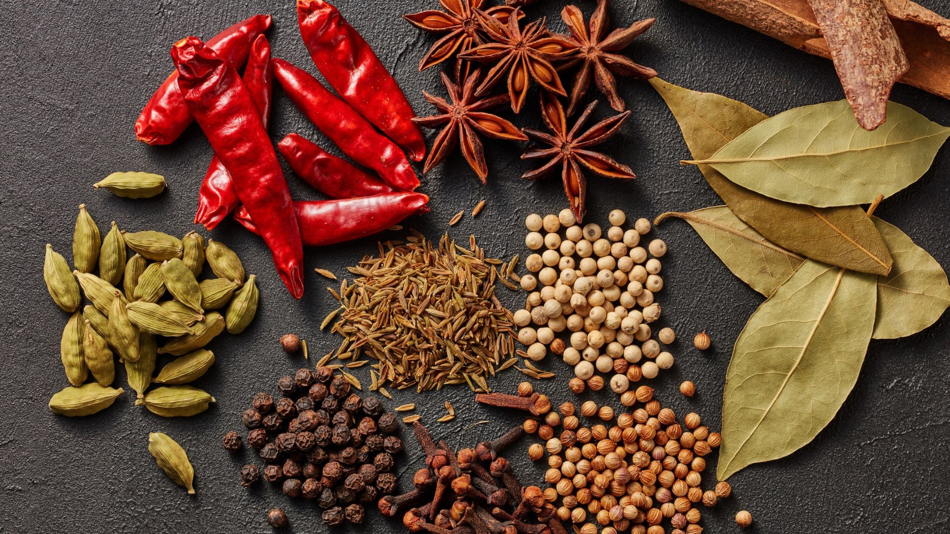 Assorted spices on dark surface.