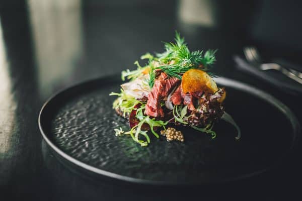 A plate of salad and meat on a black background.