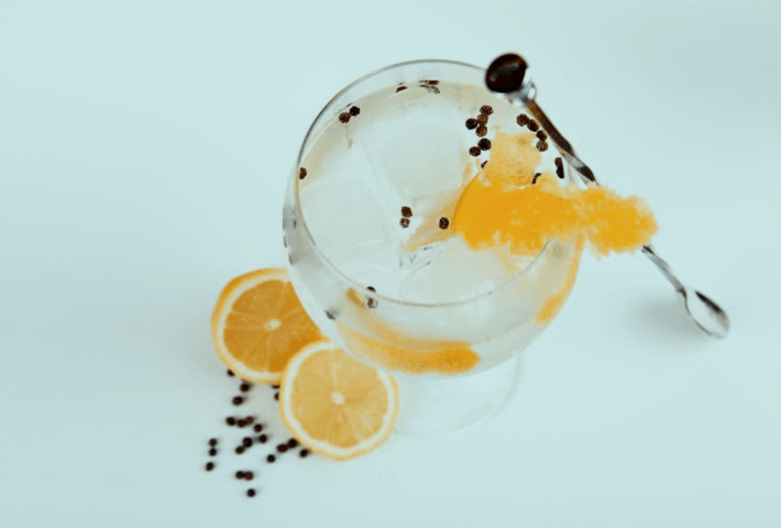Glas mit Getränk, Eis und Zitronenscheiben, helles Ambiente.