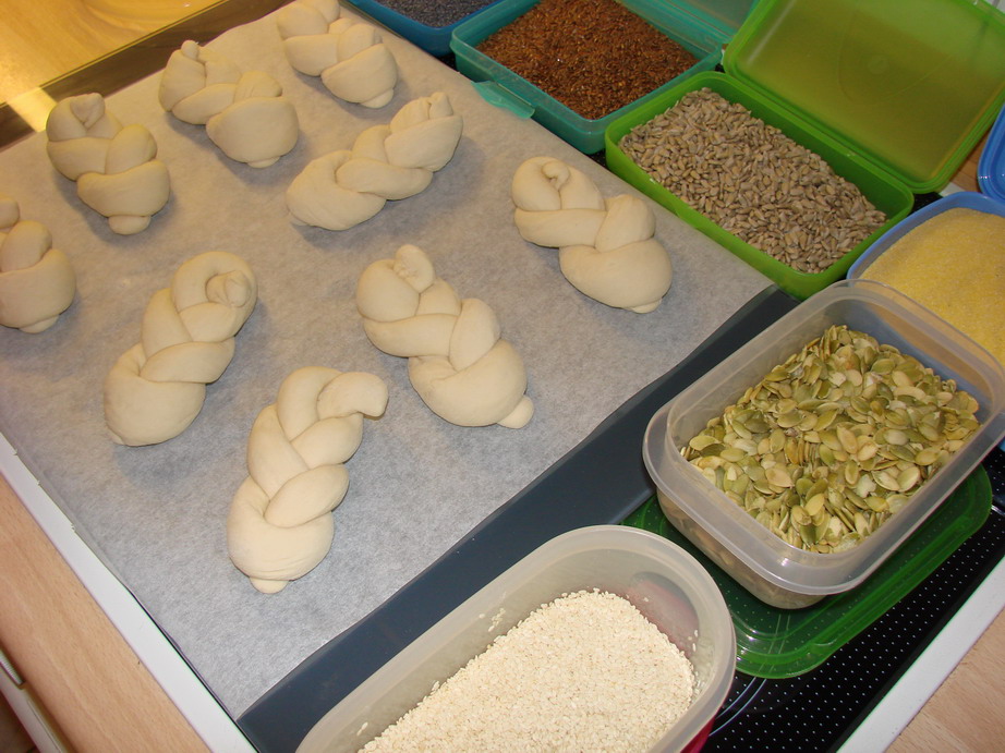 Ungebackene Brötchen mit Körnertoppings nebeneinander.