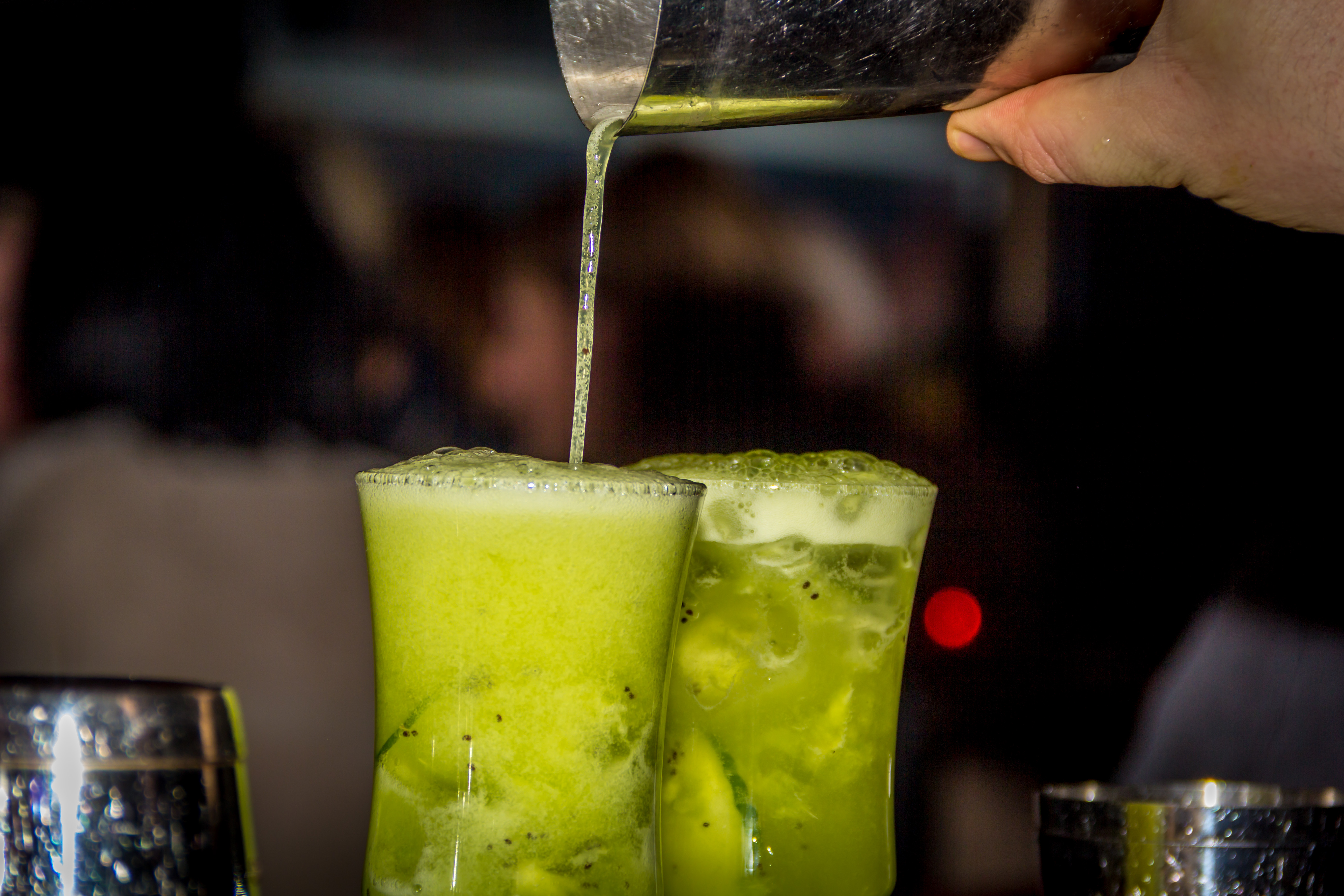 Grüne Cocktails werden in Gläser gegossen.