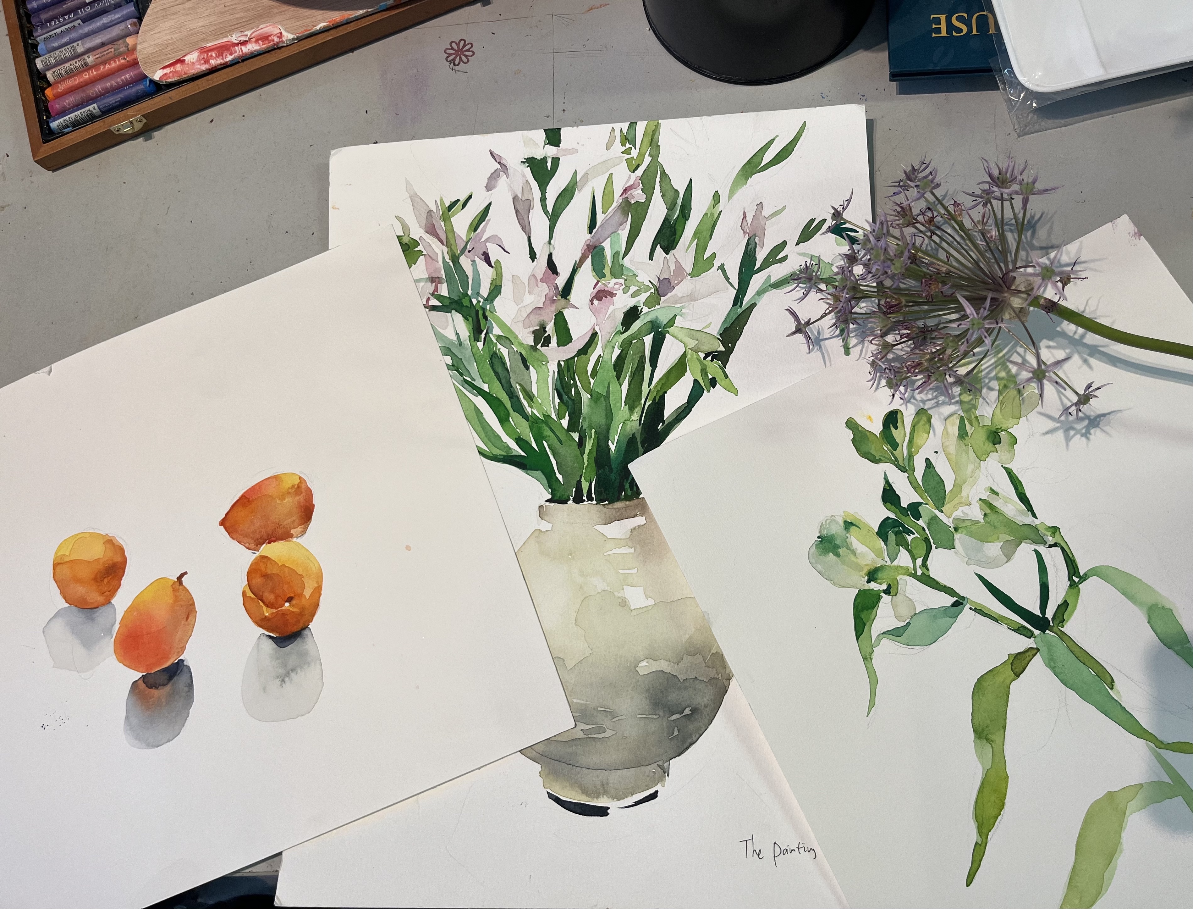 Watercolor paintings of fruit and flowers on table.