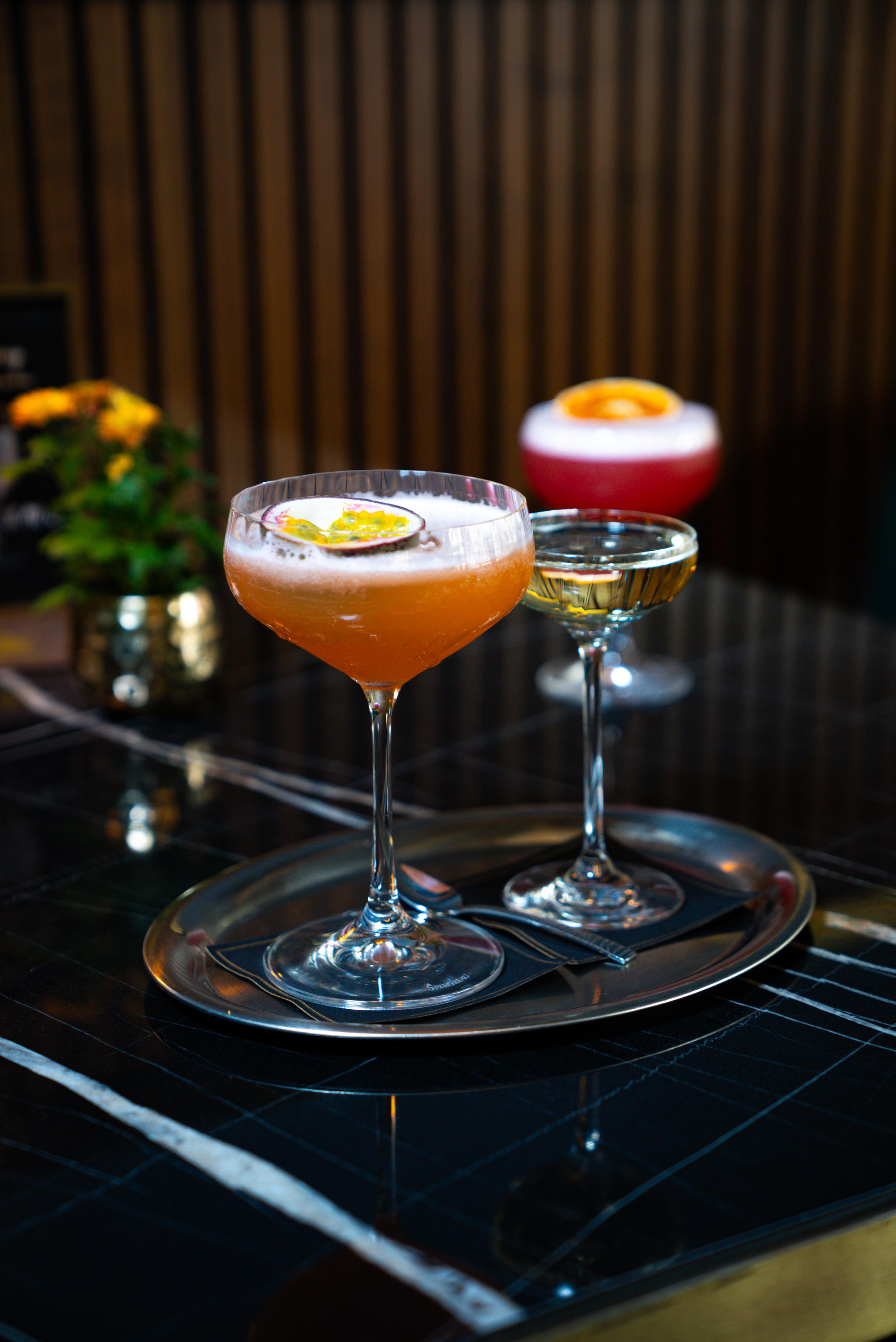 Drei Cocktails mit Fruchtgarnitur auf einem Tisch.