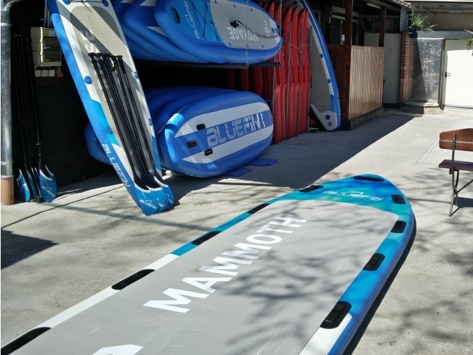 Paddleboards stacked outside under sunlight.