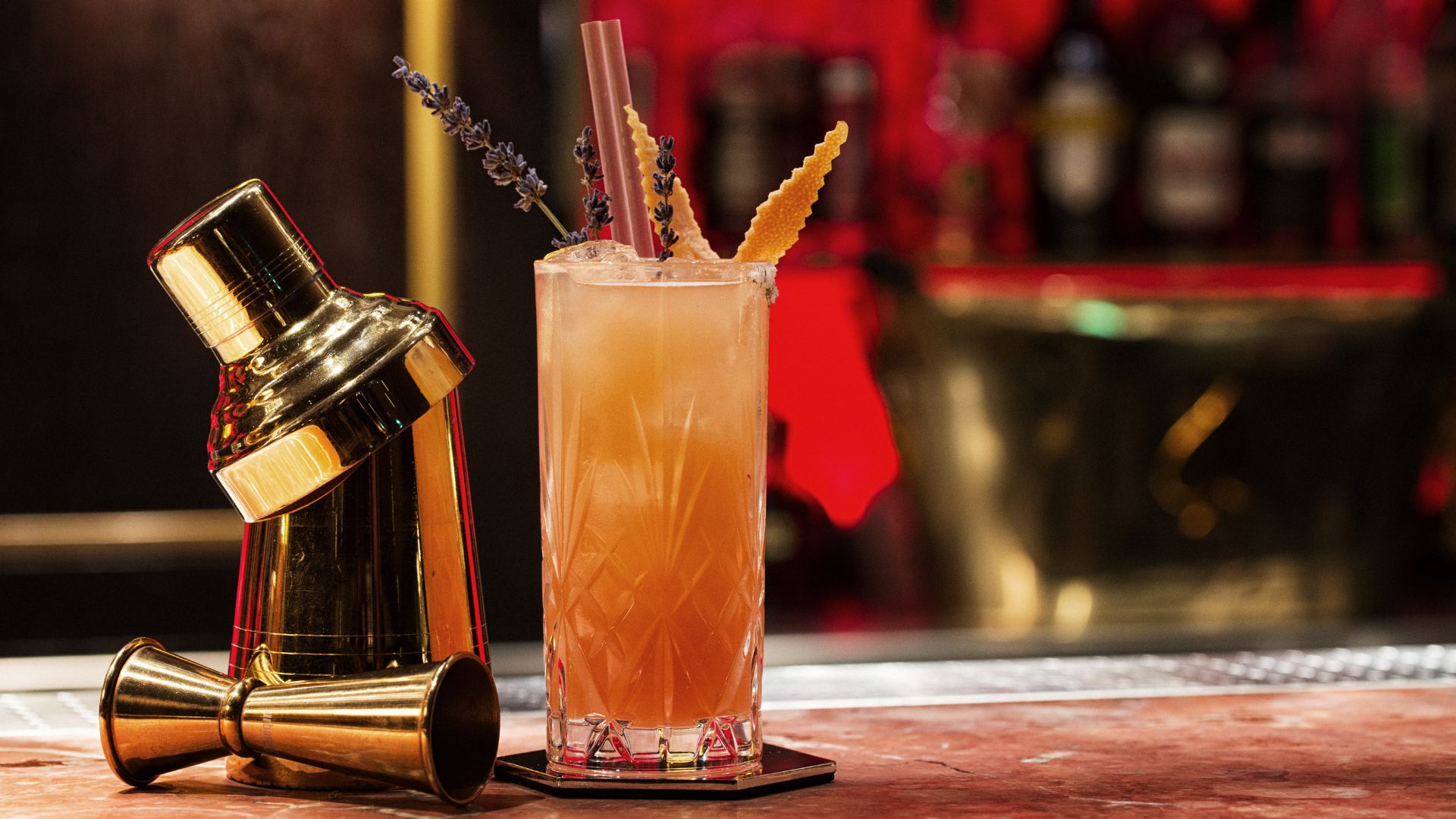 Cocktail neben Shaker auf Bartresen.