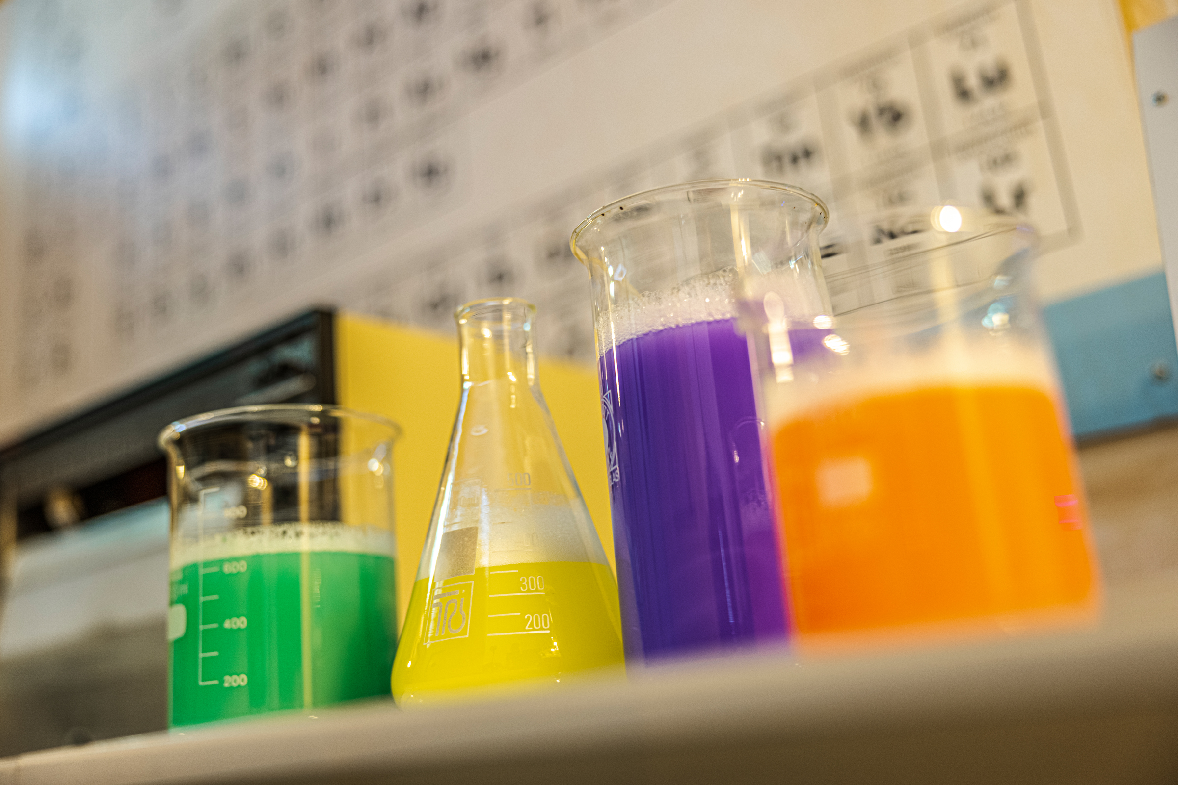 Colorful liquids in beakers and flask, laboratory background.