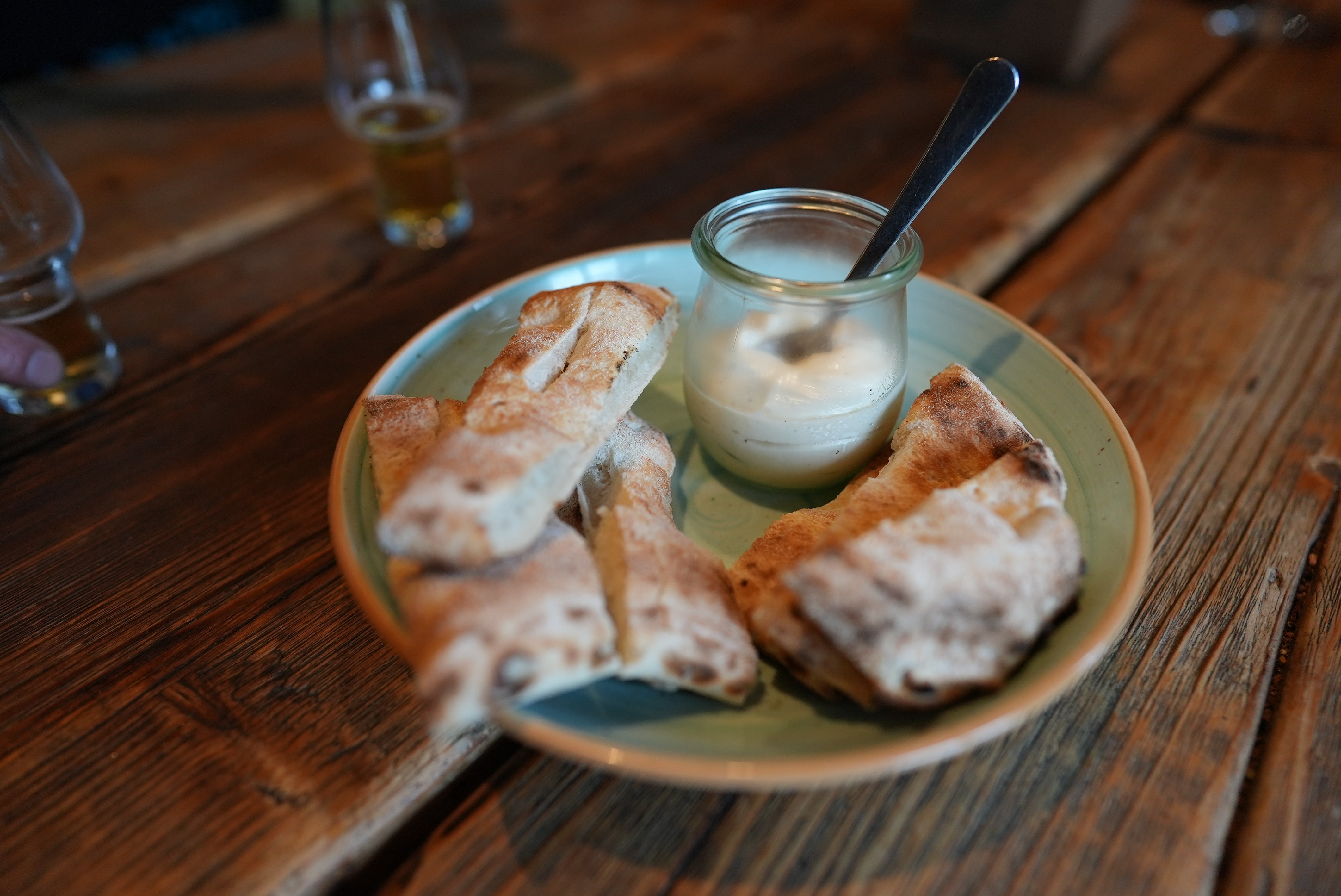 Teller mit Brot und Dip auf Holztisch.