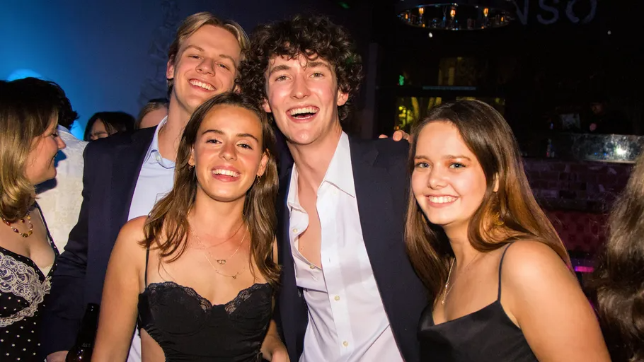 Vier Personen lächeln auf einer Party.