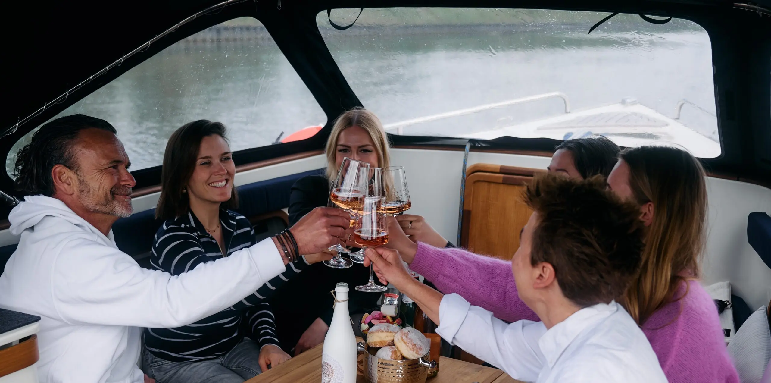 Gruppe stößt auf einem Boot mit Getränken an.