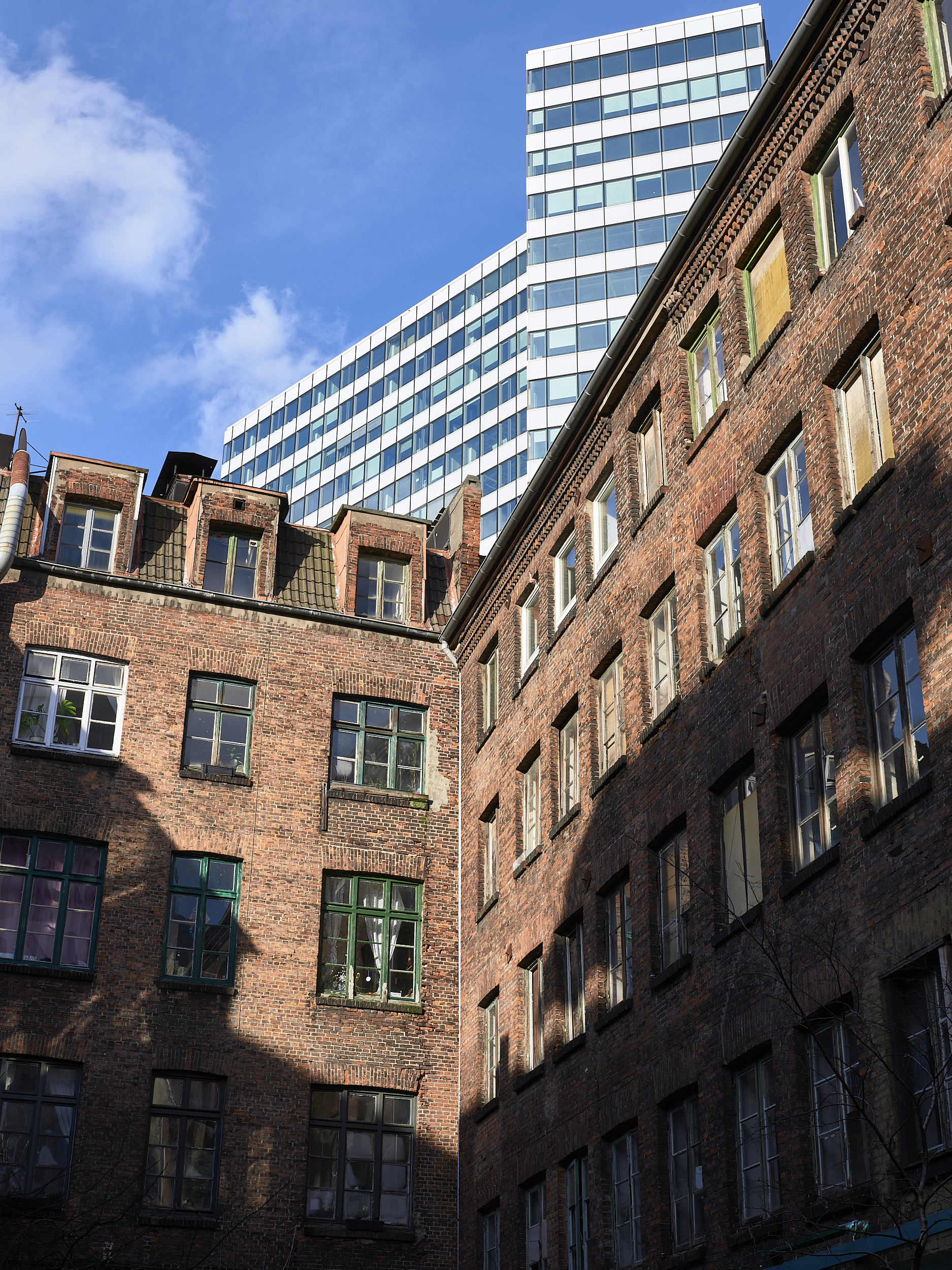 Moderner Wolkenkratzer hinter altem Backsteingebäude.