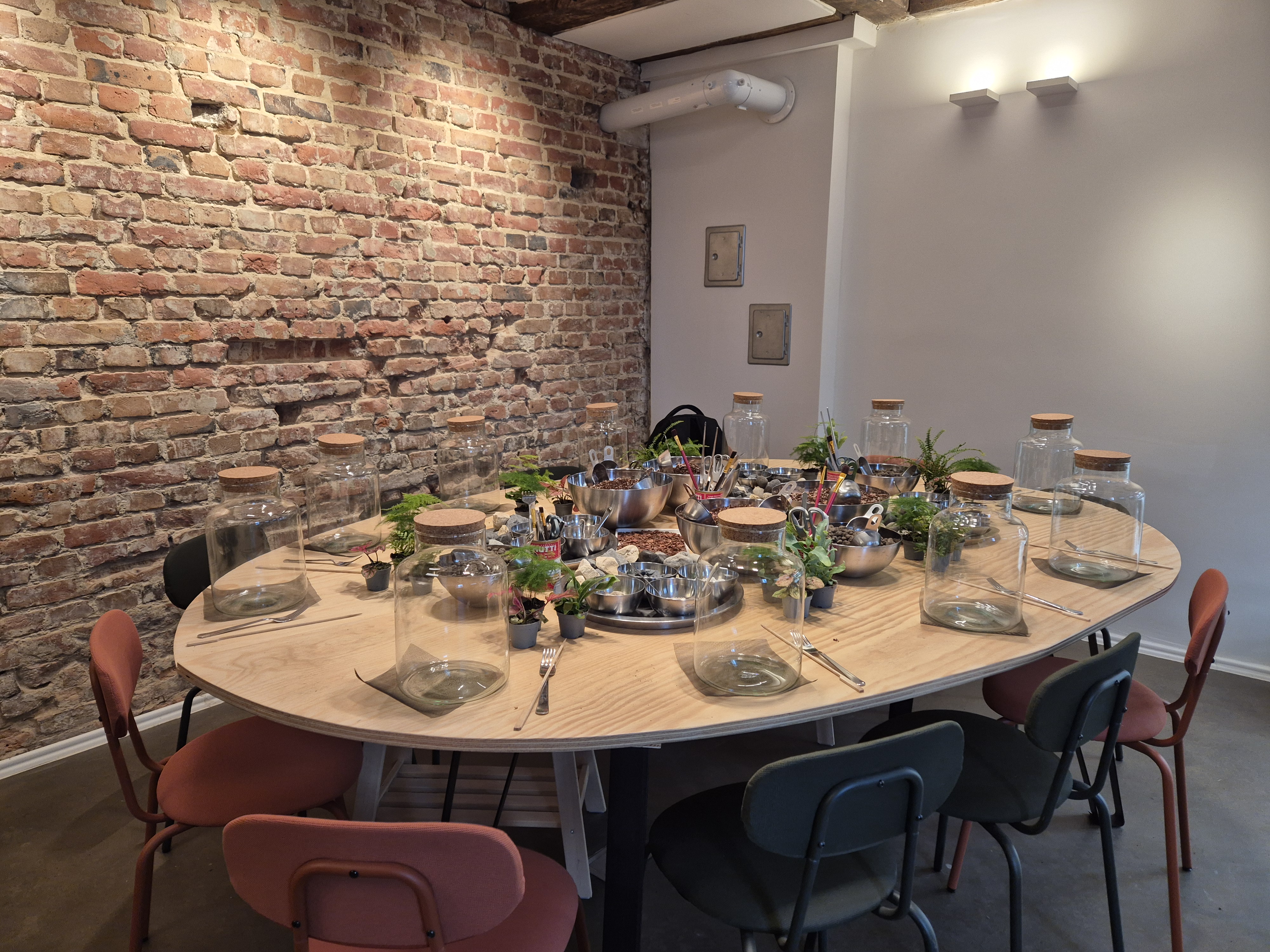 Table with jars and plants in brick-walled room.