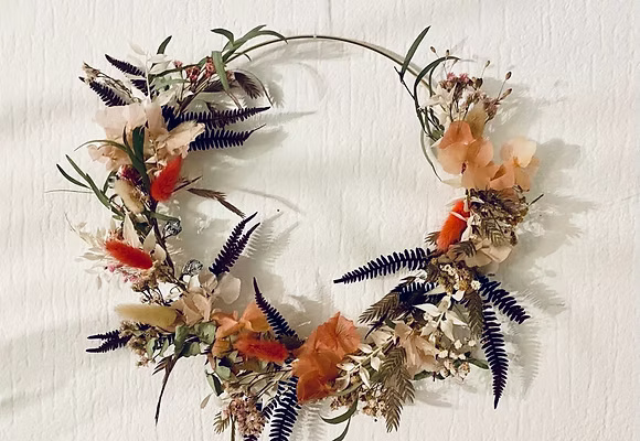Blumenkranz hängt an einer weißen Wand.